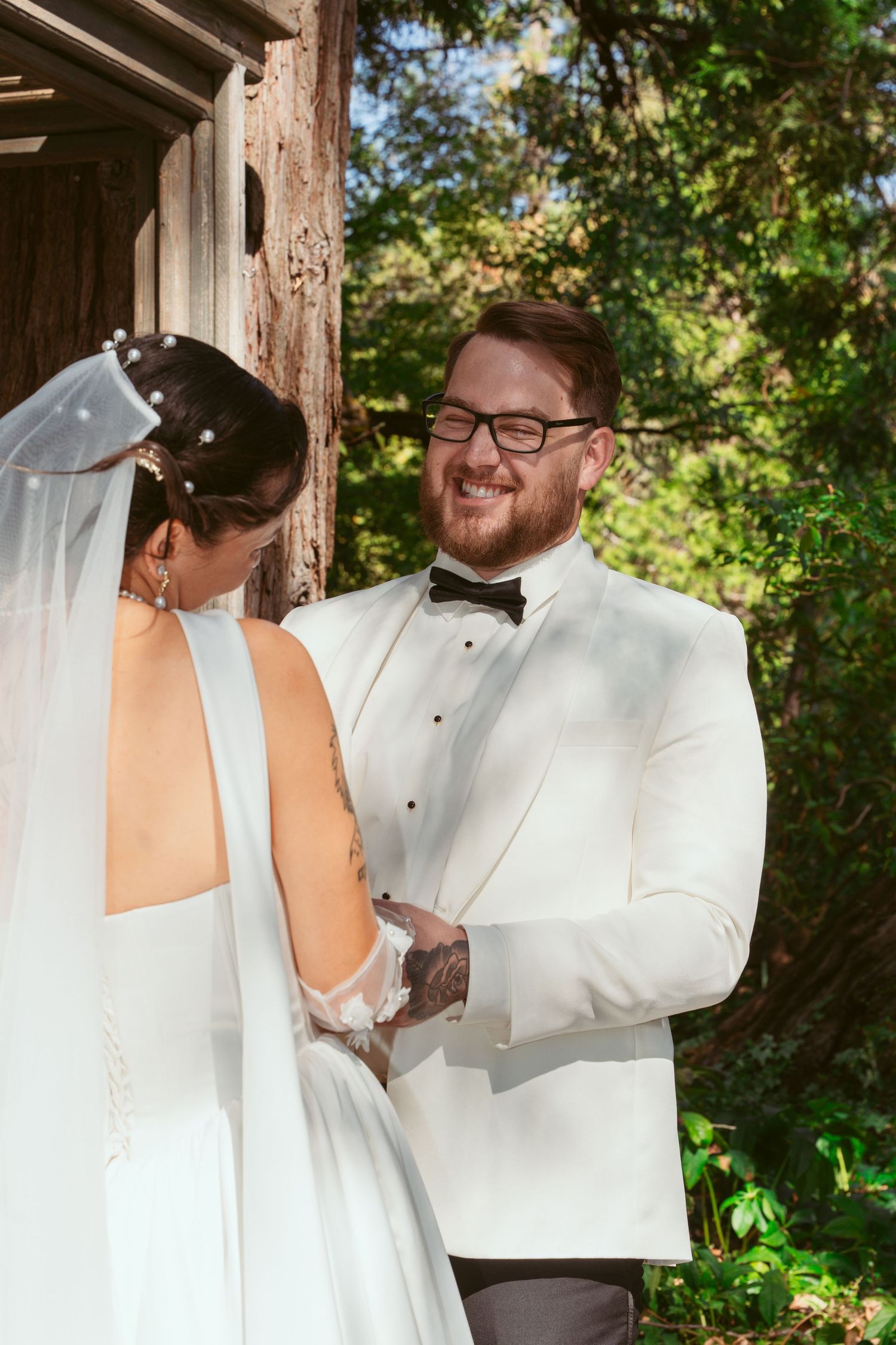 Couple shares intimate moment during wedding ceremony under wooden pergola.