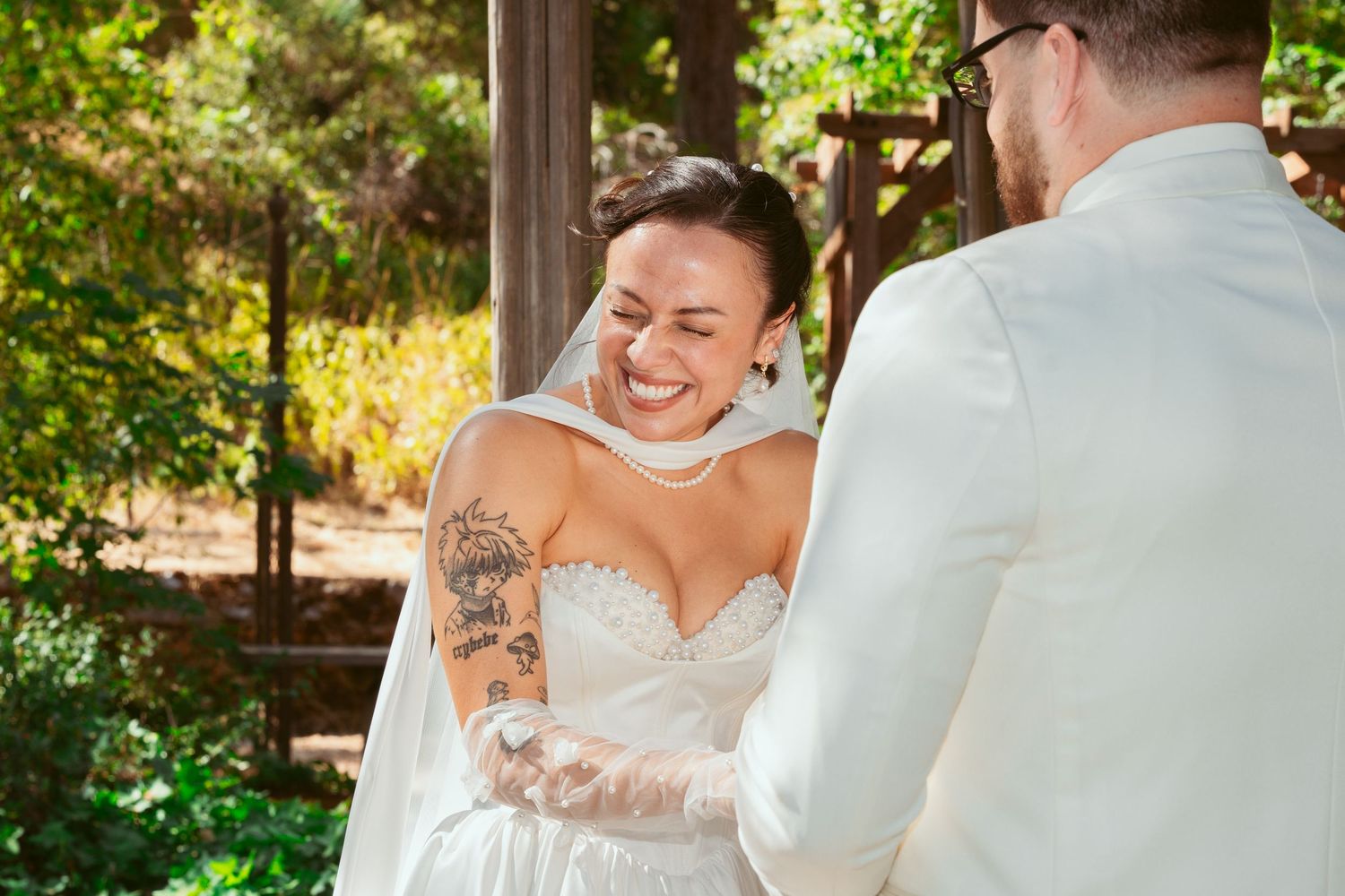 A joyful moment shared between two people during an outdoor wedding ceremony under a wooden gazebo.