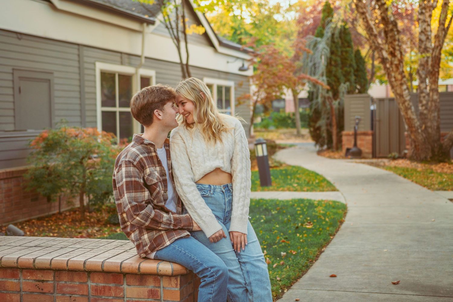 Couple enjoying autumn day together on residential sidewalk with fall foliage.