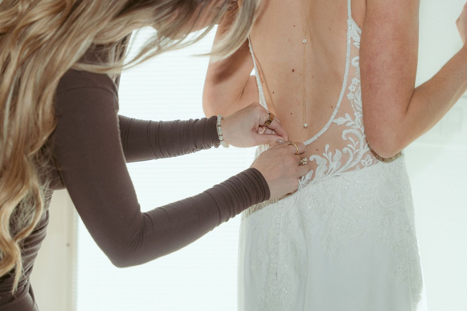 Multiple angles show the delicate process of securing a wedding dress.