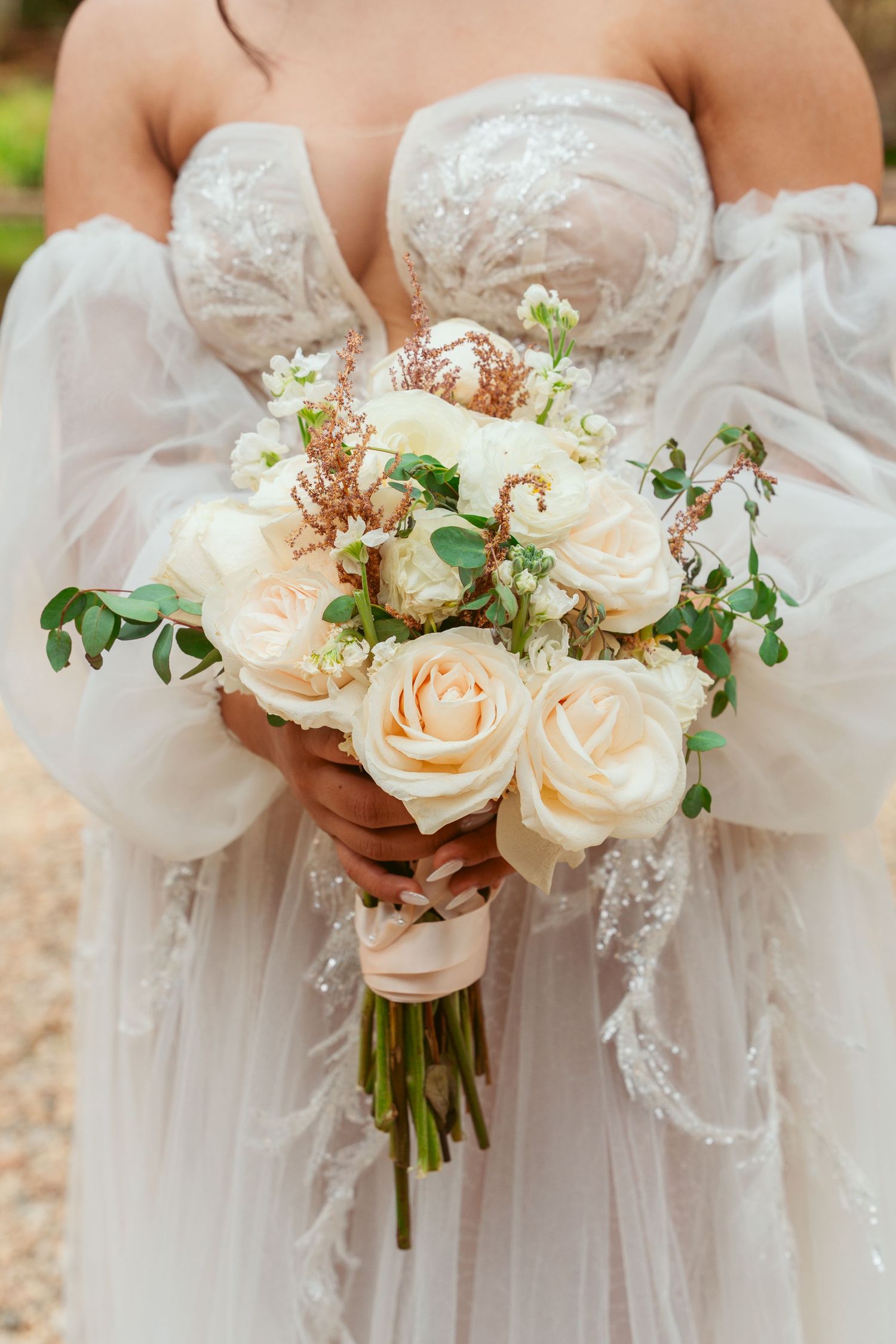 Elegant cream-colored rose bouquets held against white lace wedding dresses.