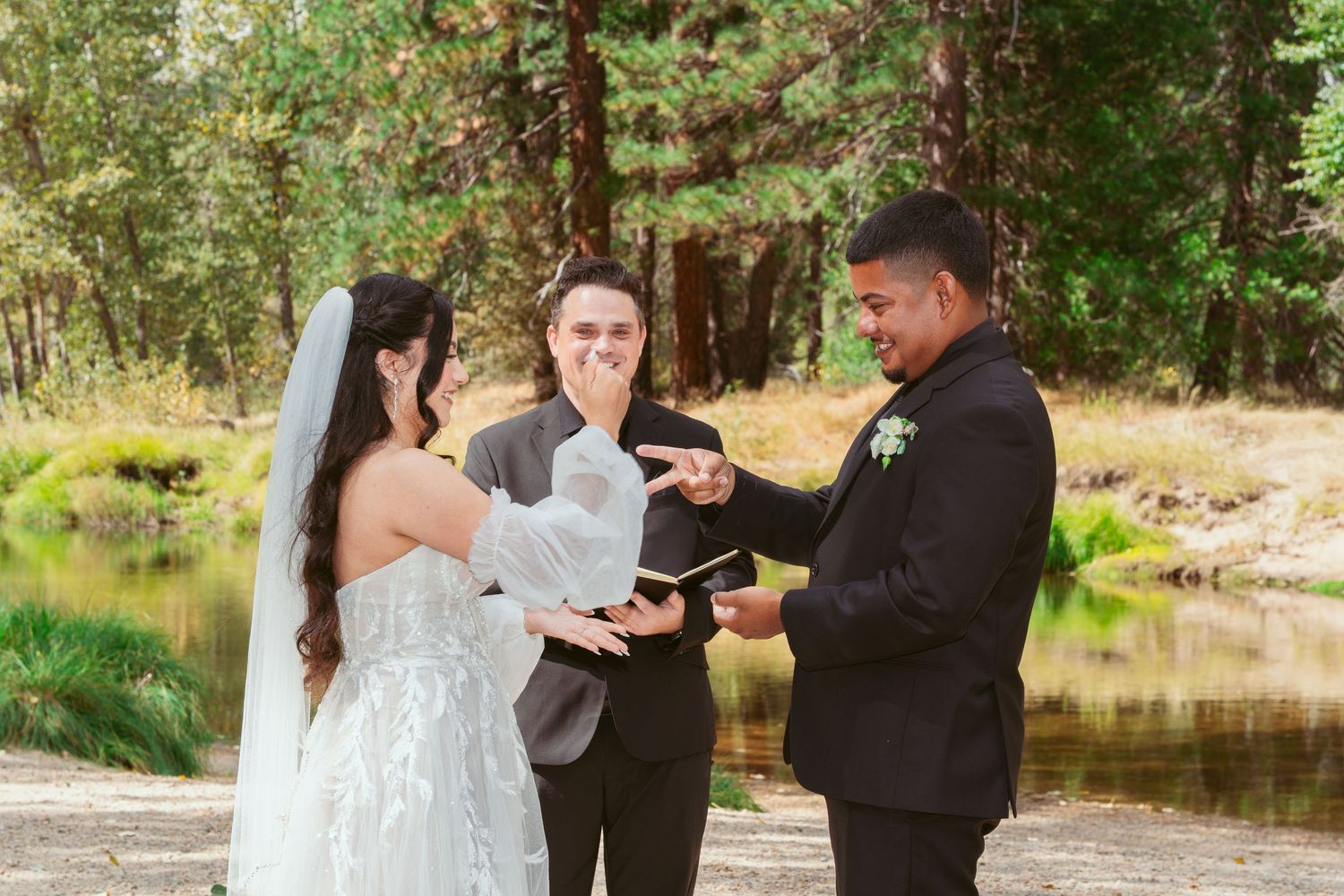 Couple exchanging vows during outdoor autumn wedding ceremony by a lake.