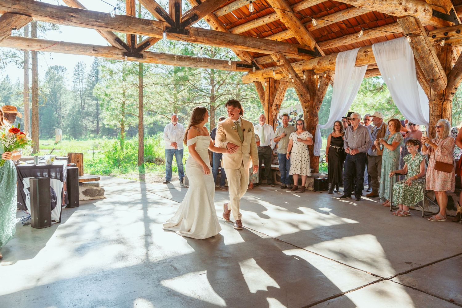 Rustic wooden pavilion decorated for a wedding ceremony with natural forest backdrop.
