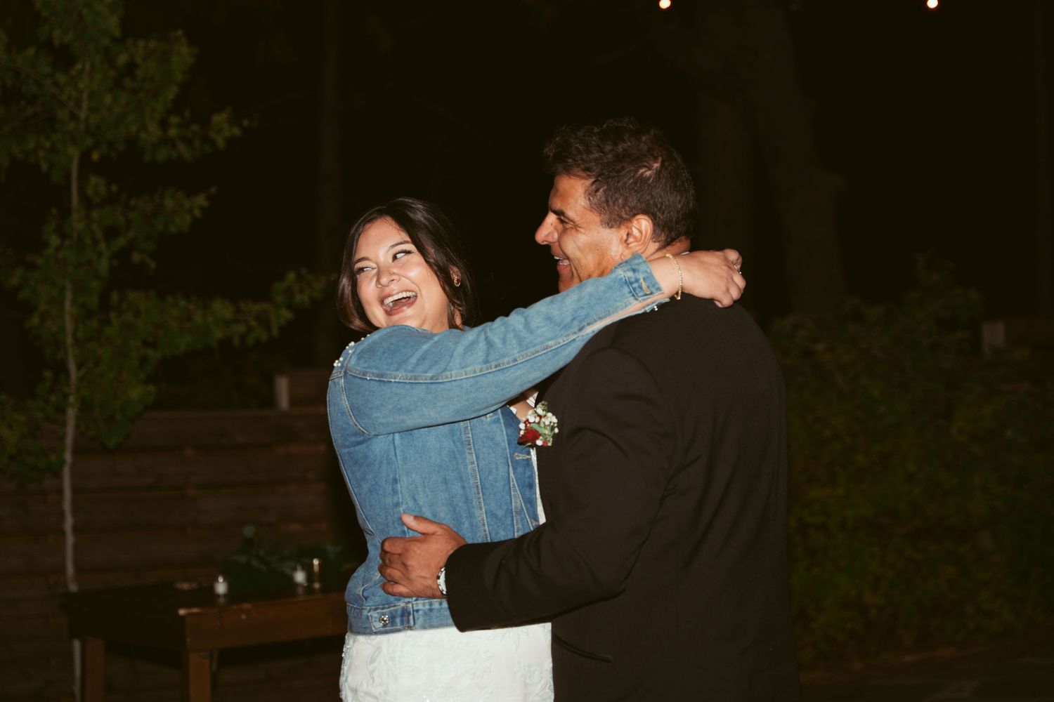 Wedding guests dancing and celebrating at an outdoor evening reception.
