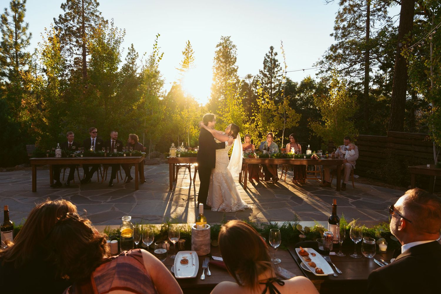 Outdoor wedding venue with pine trees and golden sunlight filtering through the branches.