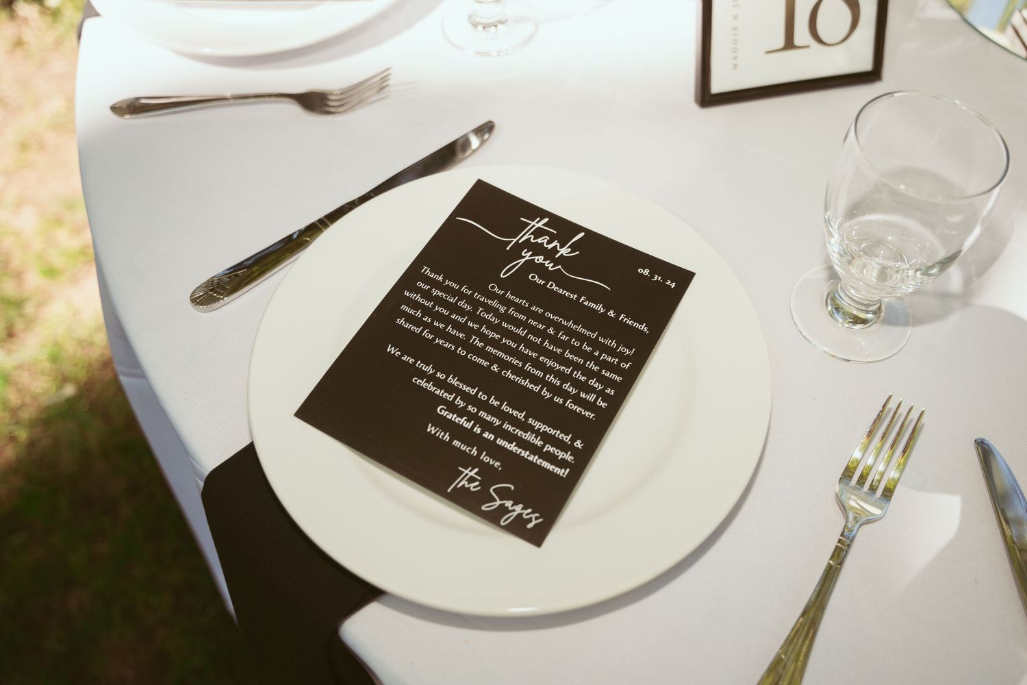 White dinner plates and elegant table settings with black menu cards at a formal wedding reception.