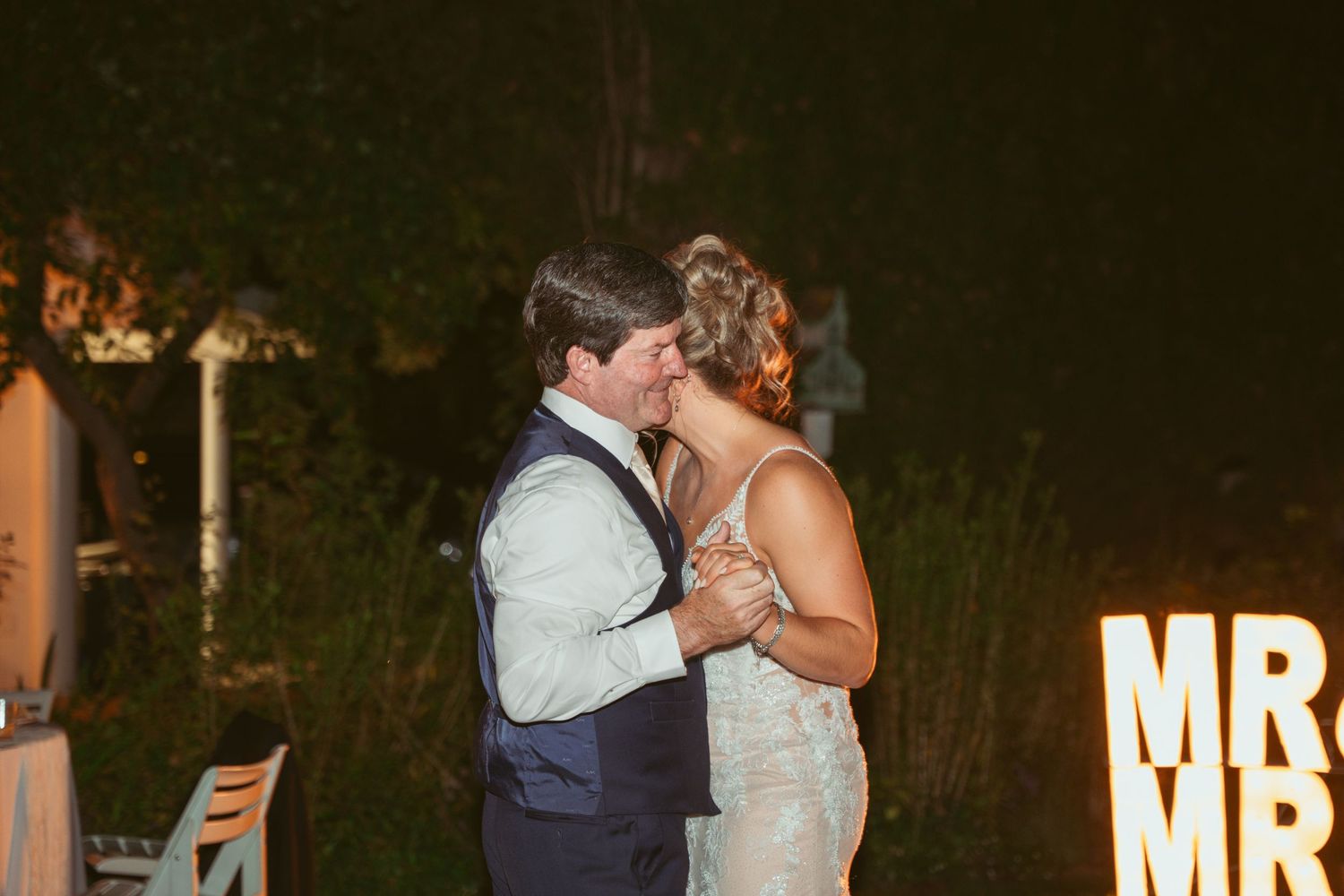 Wedding couple sharing their first dance at an outdoor evening reception.