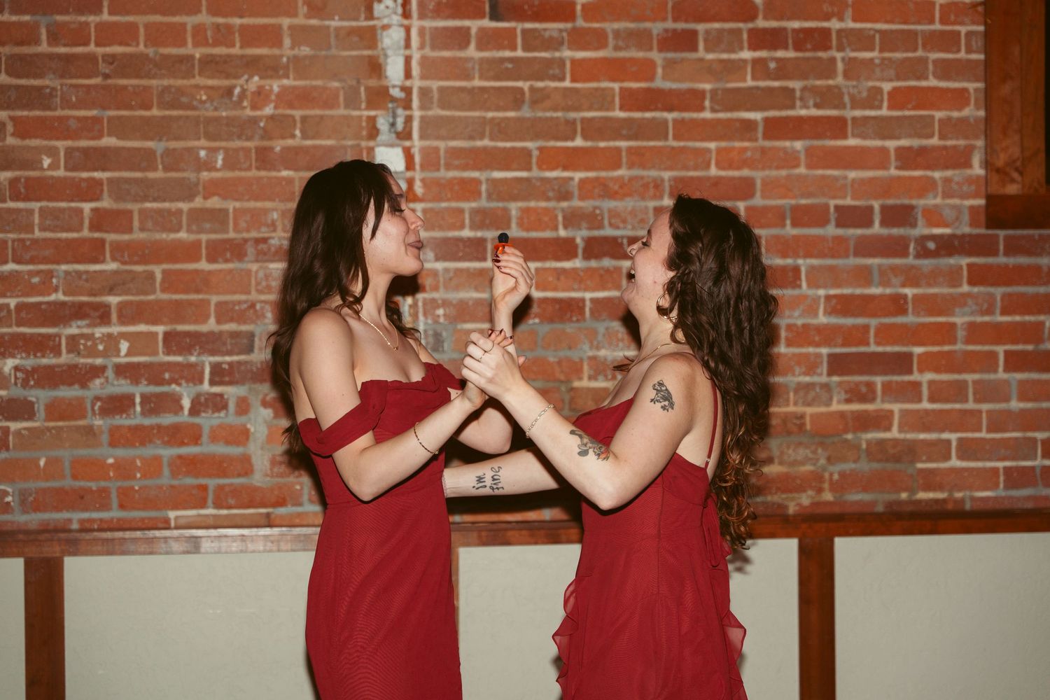 Wedding guests dancing and mingling in front of rustic brick walls.