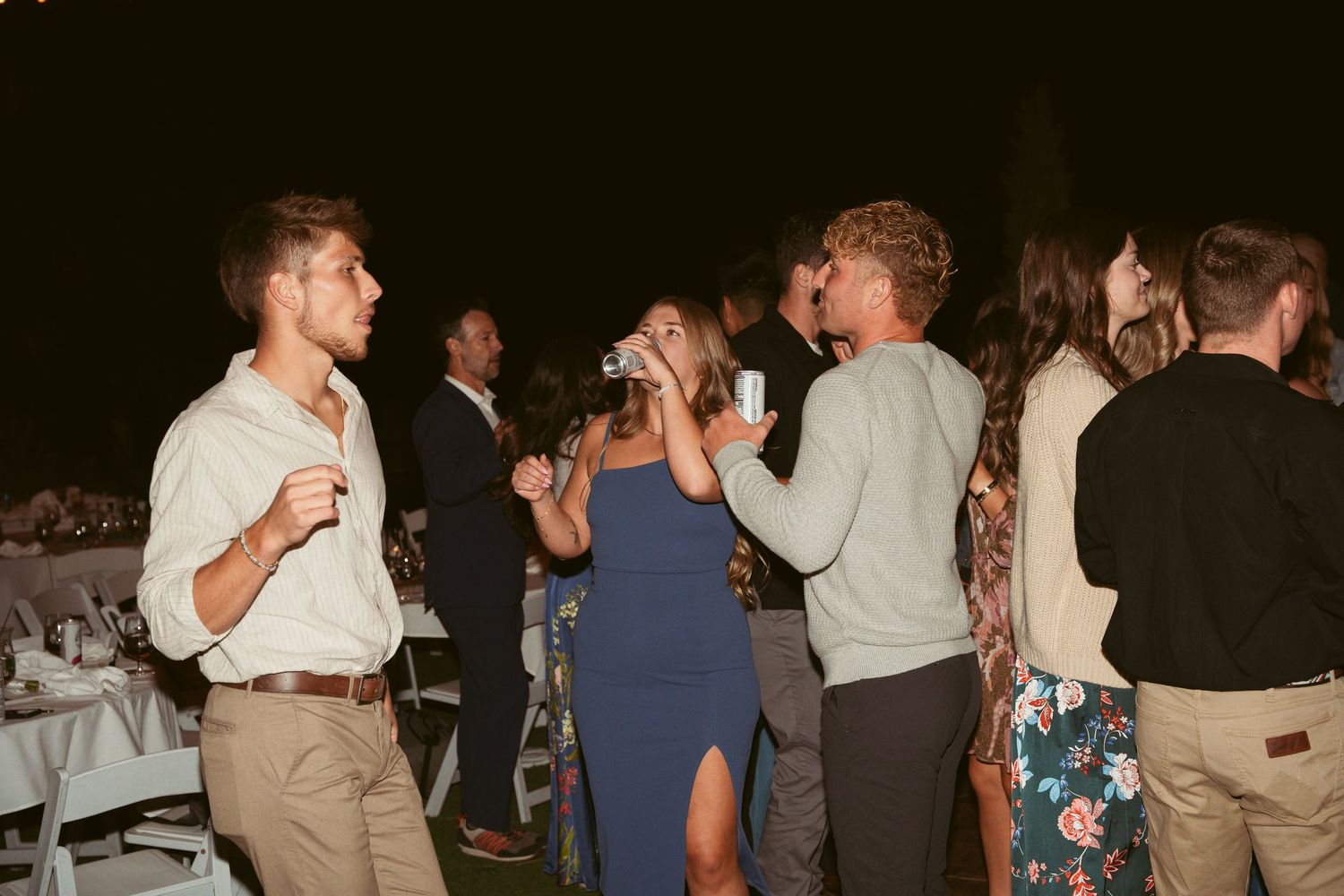 Wedding guests socializing and dancing at a lively outdoor evening reception.