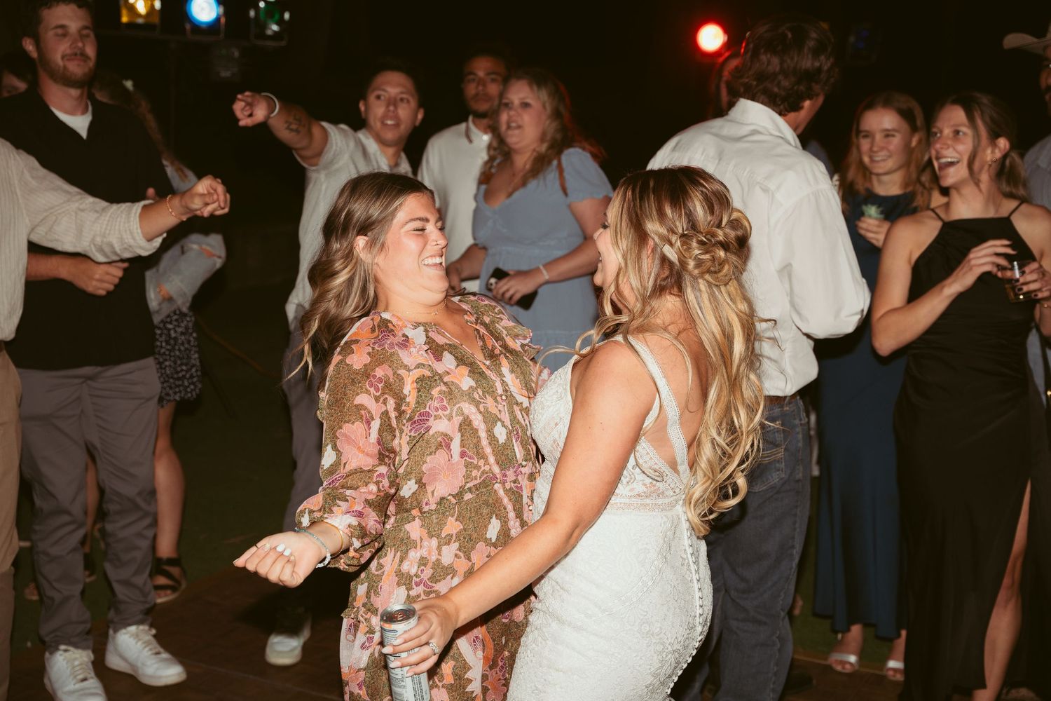 Lively dance party with guests celebrating under string lights at outdoor wedding reception.