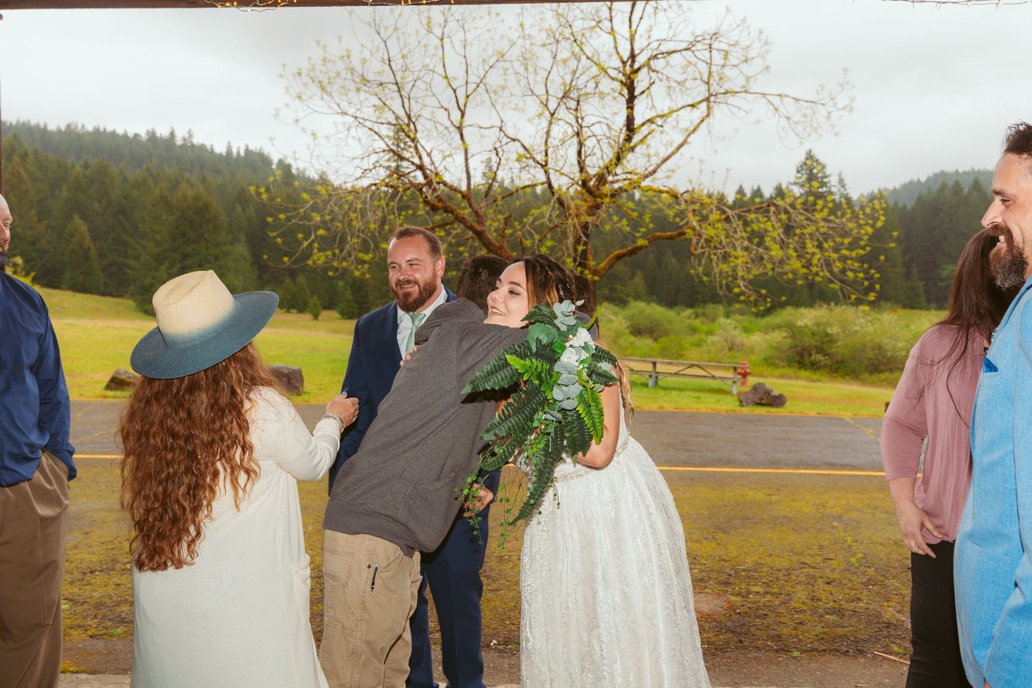 Wedding celebration candid moment outdoors with rustic backdrop and natural scenery.