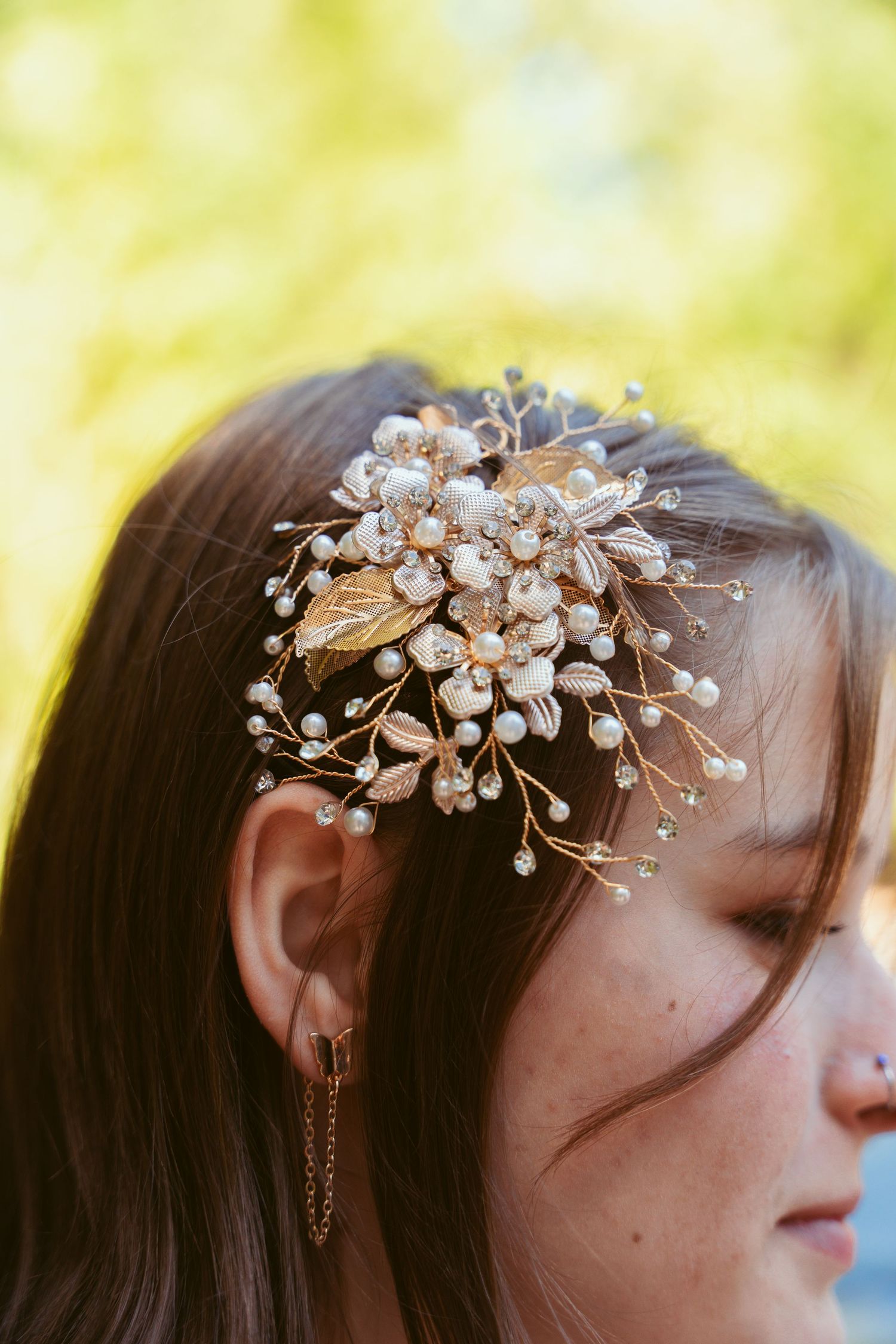 Delicate pearl and crystal hair accessory detail shot against a soft yellow background.