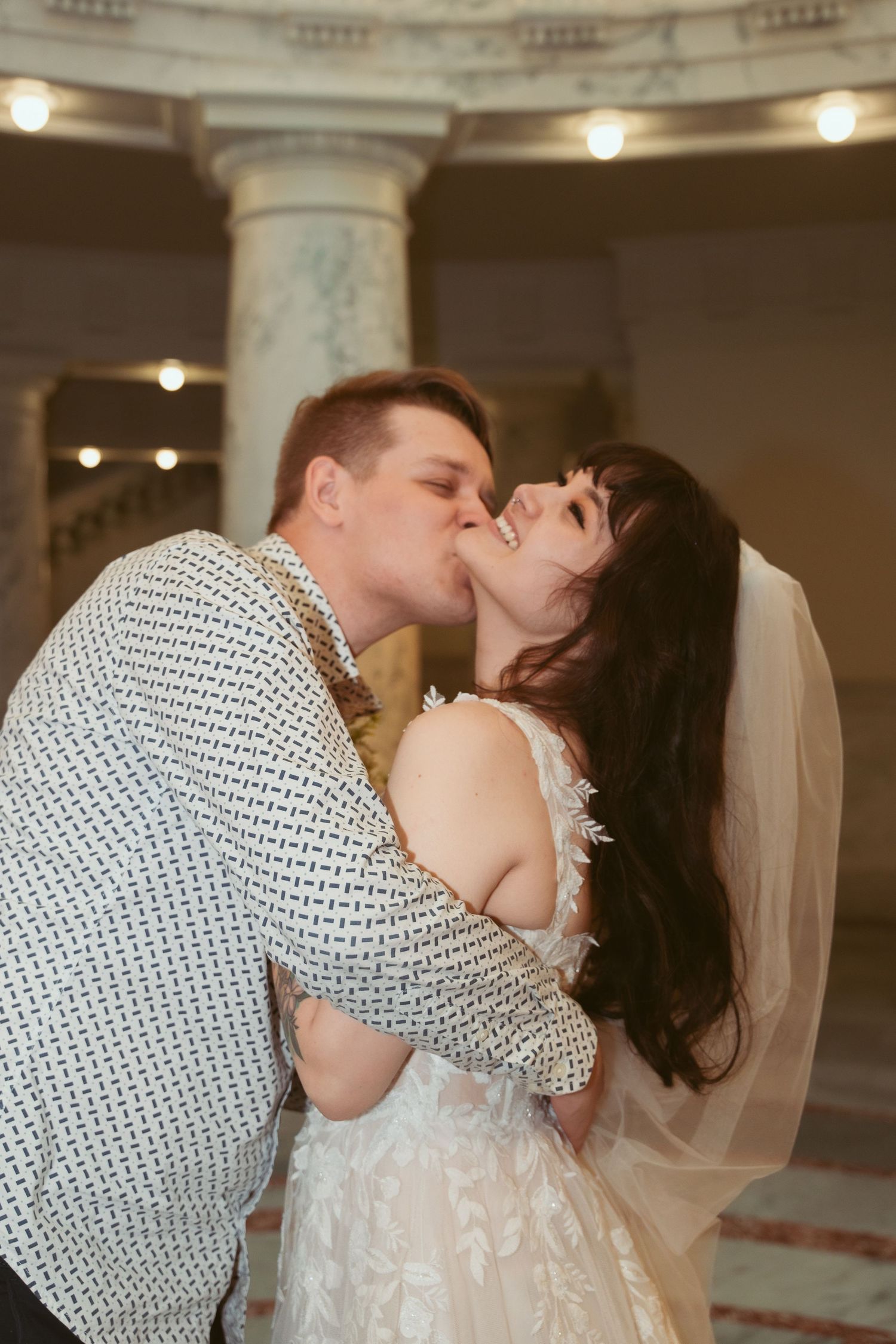 Romantic moment between newlyweds under ornate indoor lighting during their first dance.