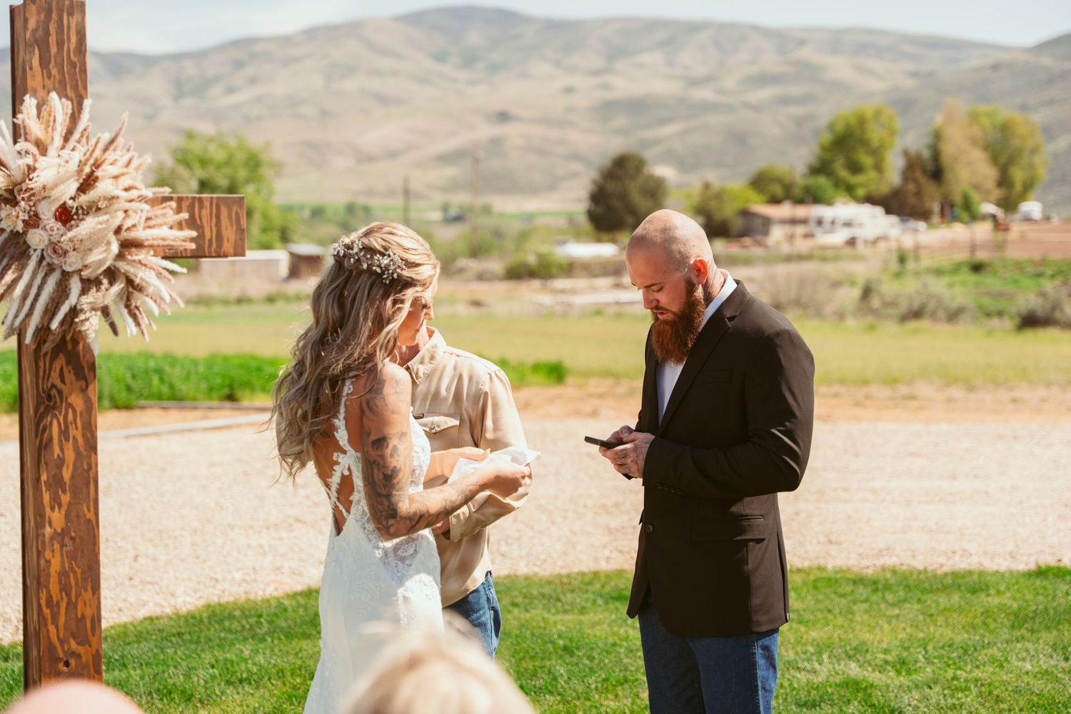 Intimate wedding ceremony moment with wooden post and mountain backdrop.