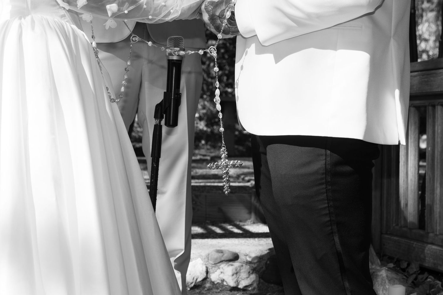 A black and white capture of wedding ceremony details under a wooden structure.