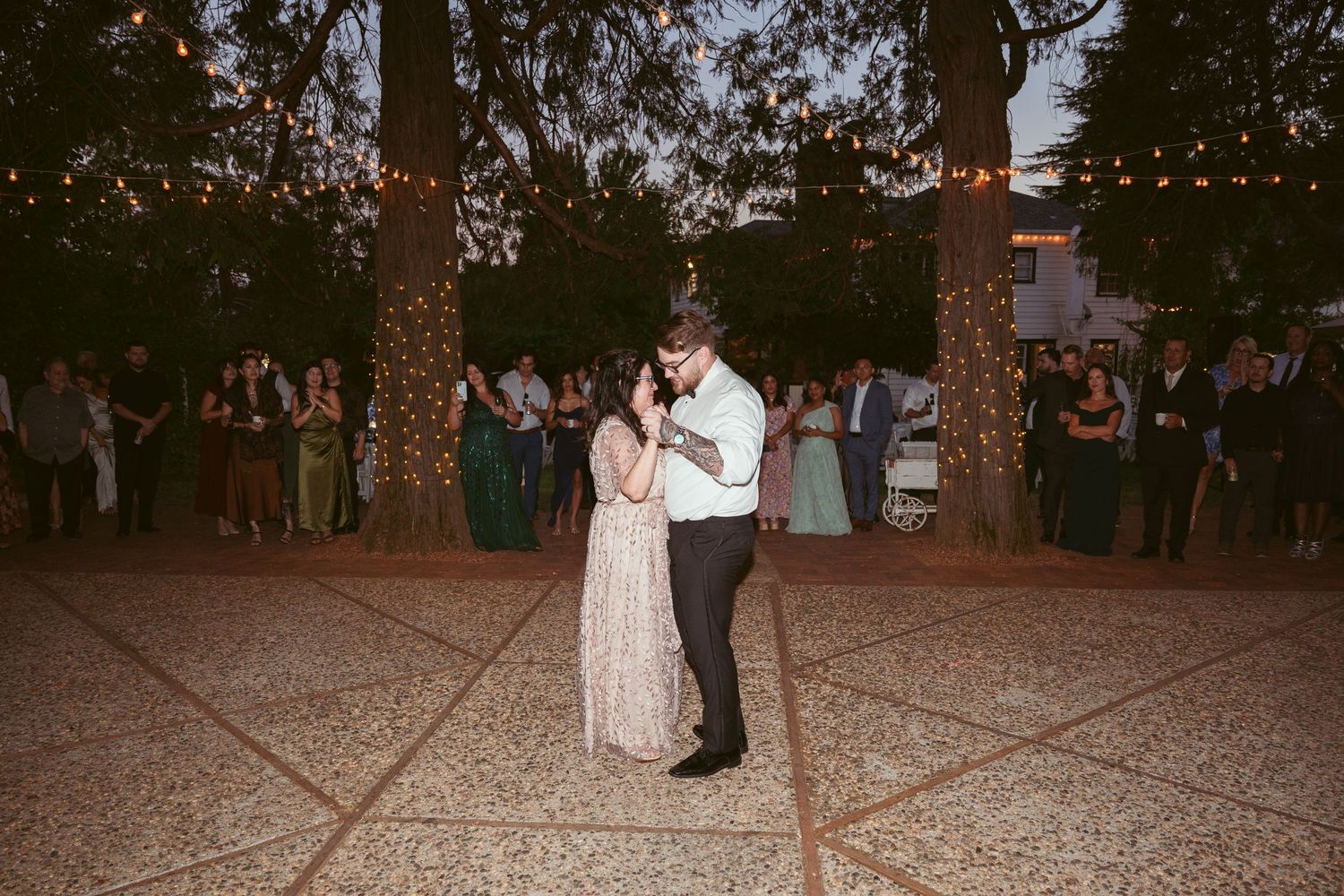 Wedding celebration on an outdoor dance floor with string lights illuminating the evening festivities.