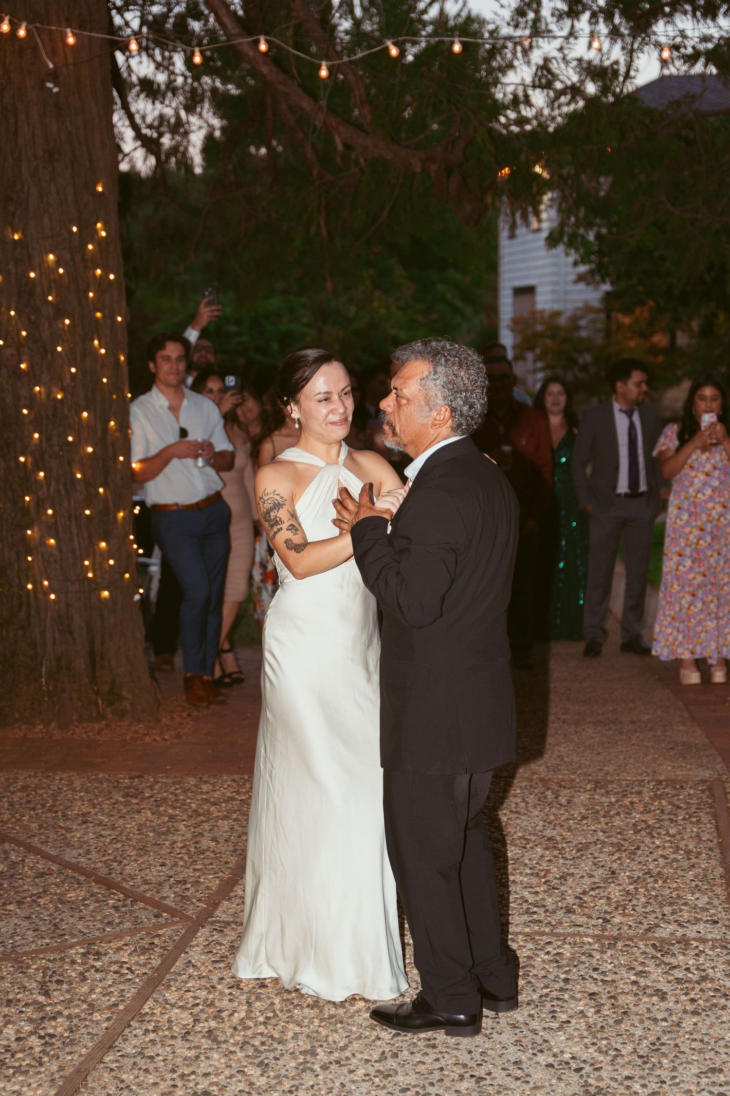 Romantic evening dance at an outdoor wedding reception with string lights creating a magical atmosphere.