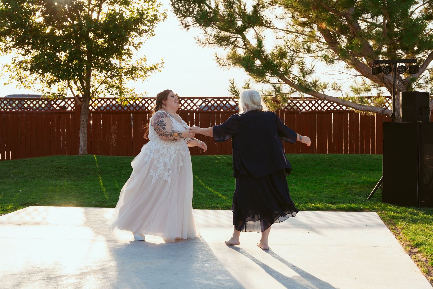 Couple dancing together at an outdoor wedding reception during golden hour.