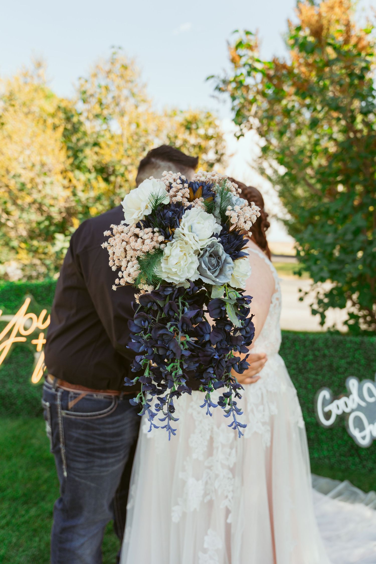 Wedding couple embracing outdoors with beautiful floral arrangements and autumn scenery.