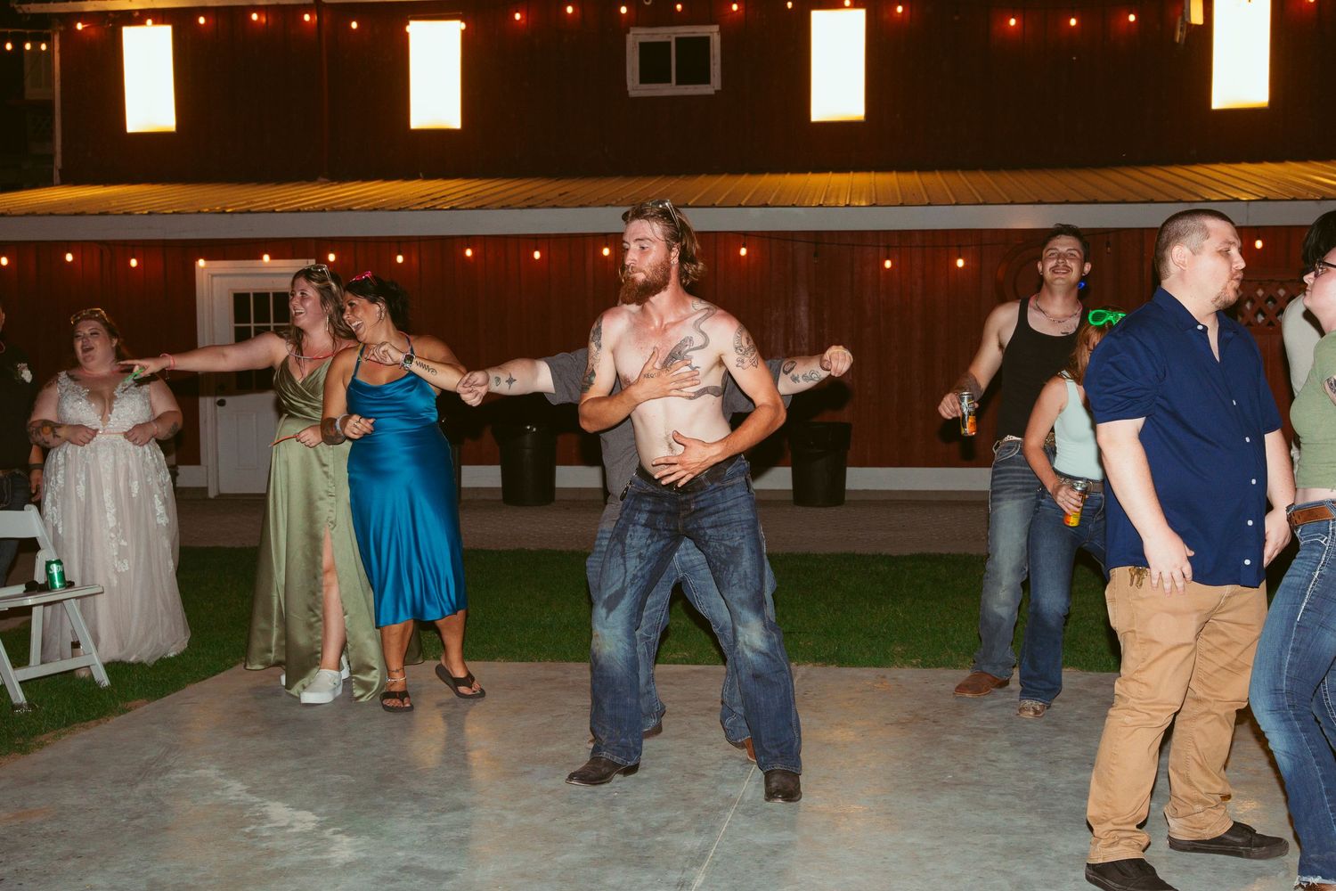 People dancing and celebrating on an outdoor patio decorated with string lights.