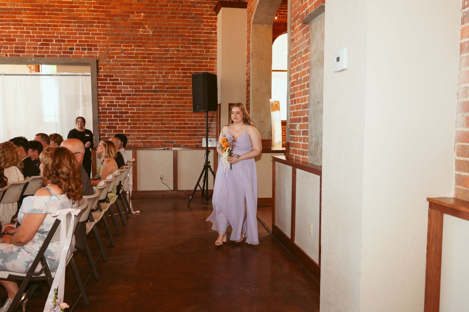 Wedding celebration in progress inside a renovated brick building with string lights and white decor.