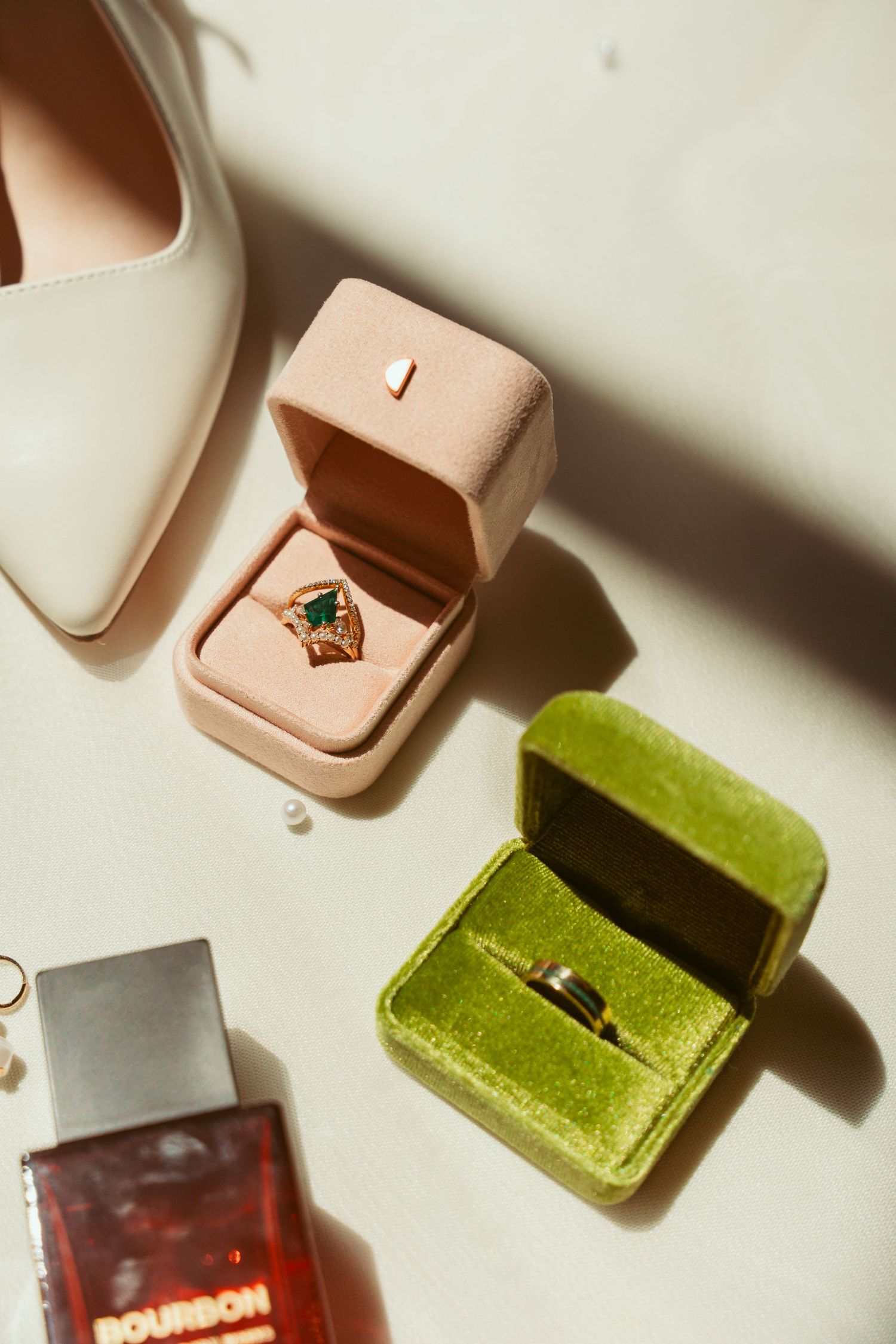 Collection of velvet ring boxes in blush, green, and burgundy colors on white surface.