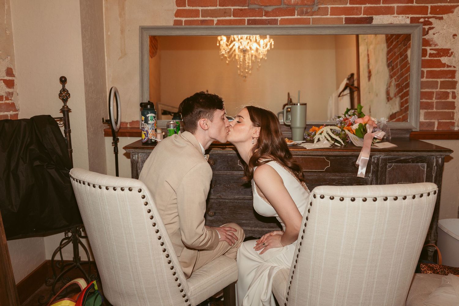 Wedding party dining at an elegant indoor venue with exposed brick walls and chandeliers.