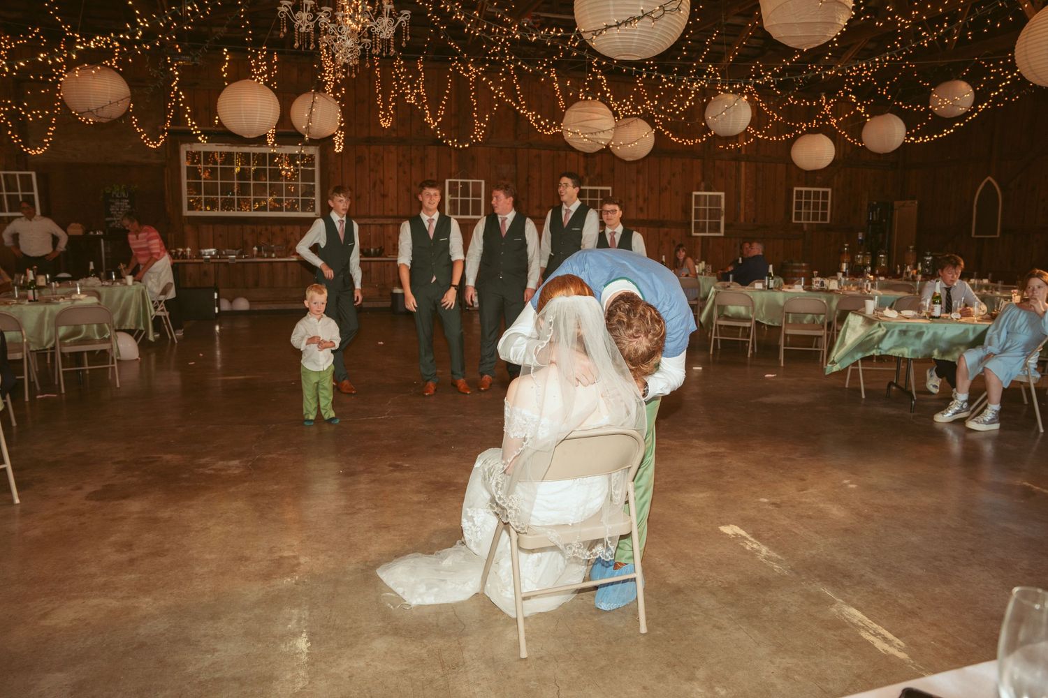Wedding reception in a rustic barn venue decorated with string lights and paper lanterns.