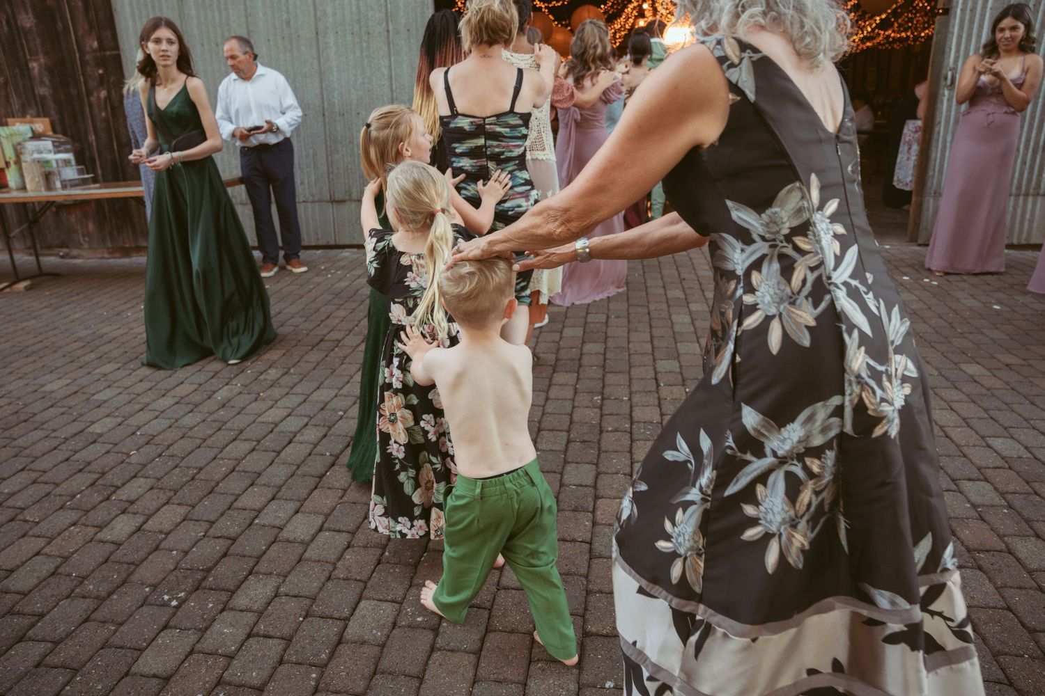 Wedding celebration features synchronized dance moves on outdoor patio with string light decor.