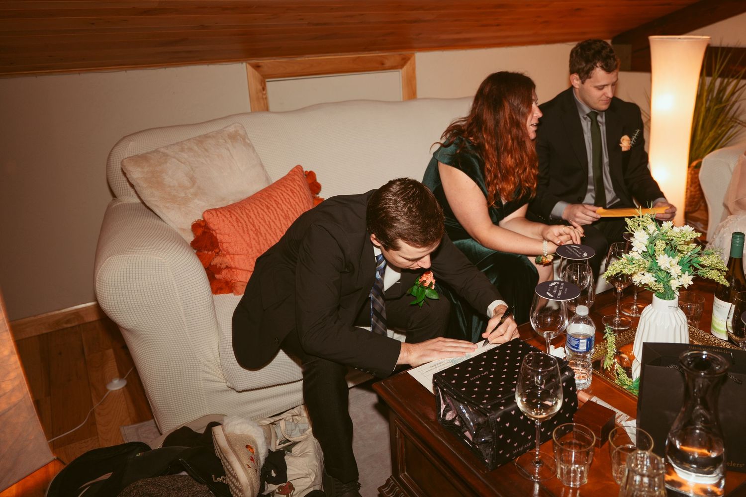 Indoor wedding reception scene with document signing at wooden table.