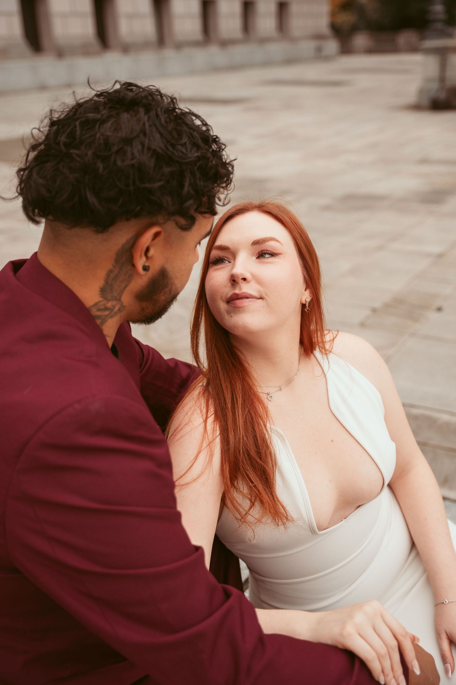 An intimate portrait of a couple in contrasting burgundy and white attire sharing a tender moment.