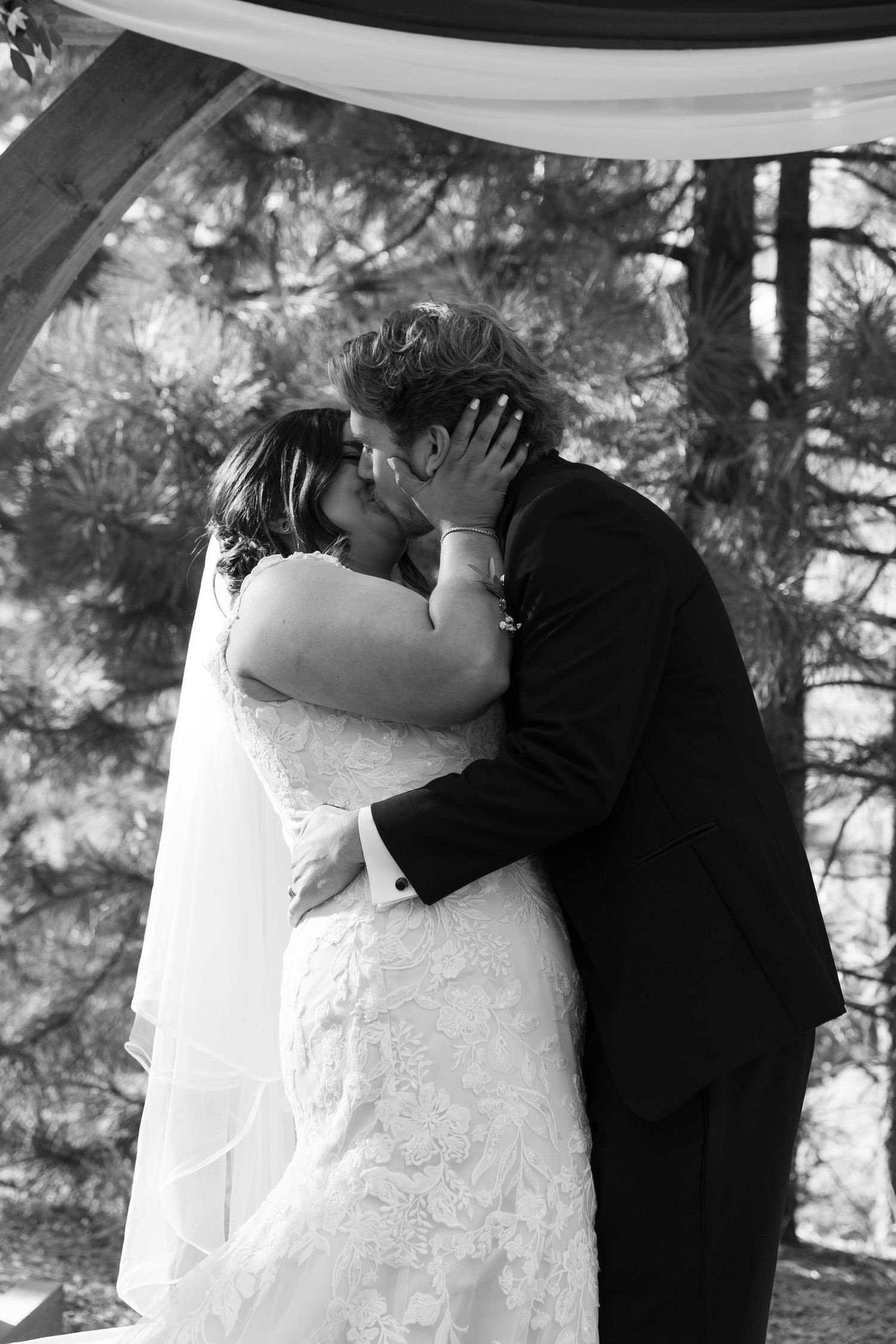 Black and white photos capturing the newlyweds' first kiss during their forest wedding ceremony.