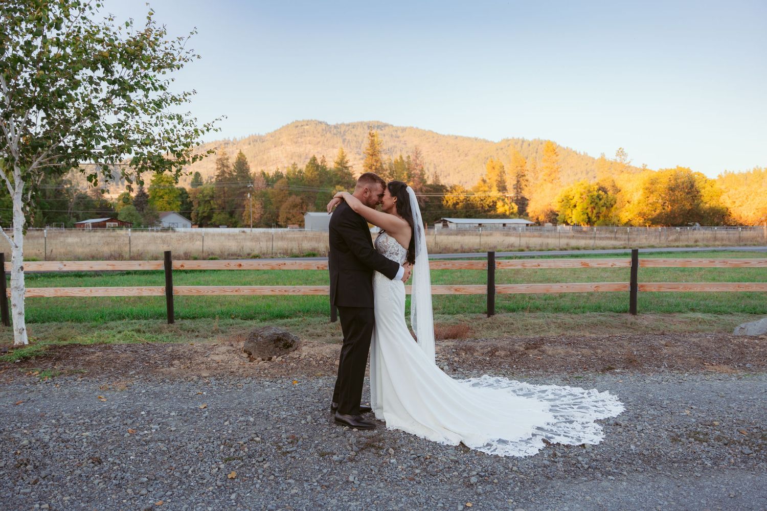 Wedding couple poses against mountain landscape with dramatic sunset lighting.