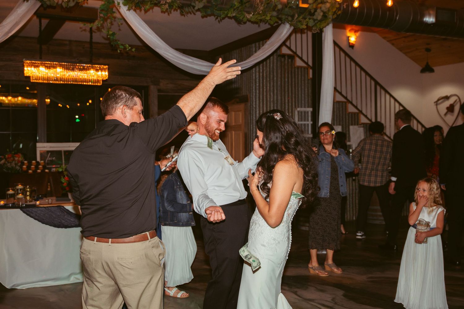 Couples dancing together at an evening wedding reception with decorative white draping.