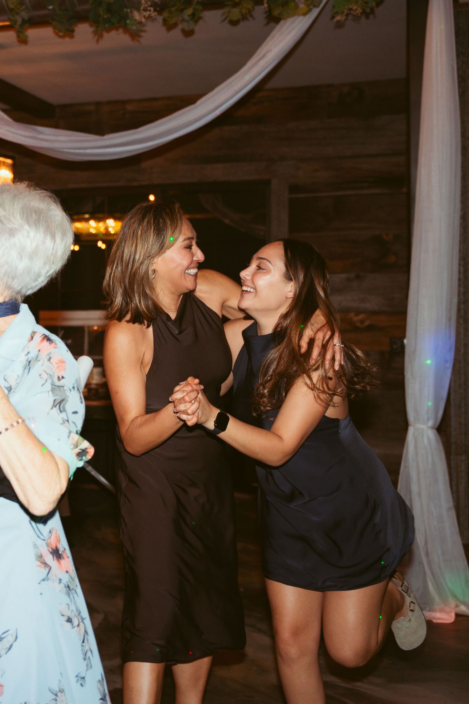 Party guests dancing and celebrating together under white fabric decorations.