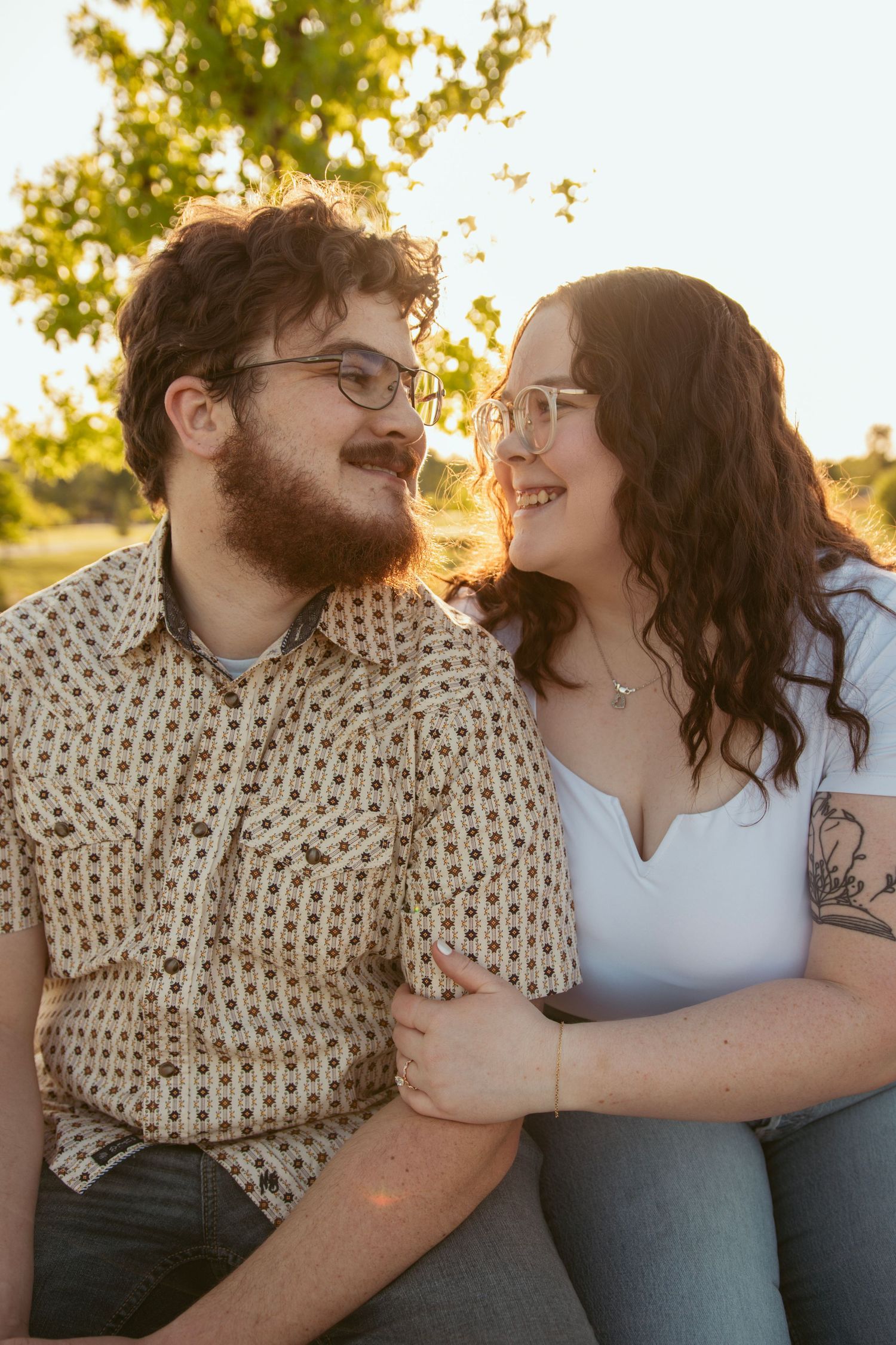 Couple sitting close together sharing intimate laughs in warm evening light.