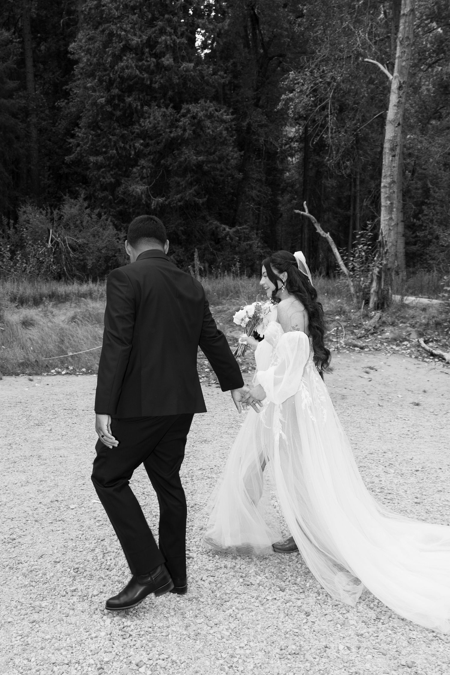 Black and white wedding photos showing couple walking together on natural path.