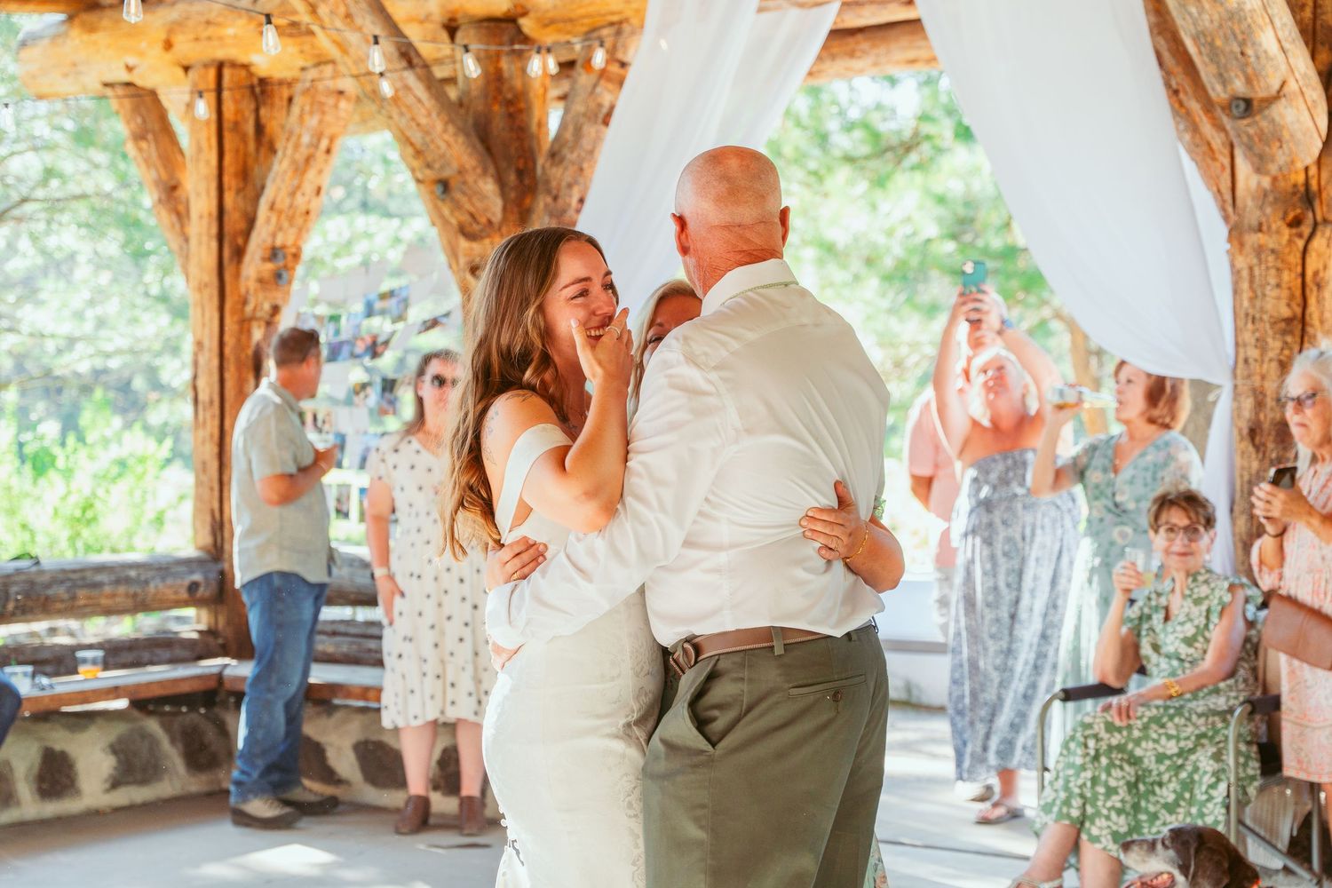 Romantic dance moment under a wooden pavilion with natural forest backdrop.