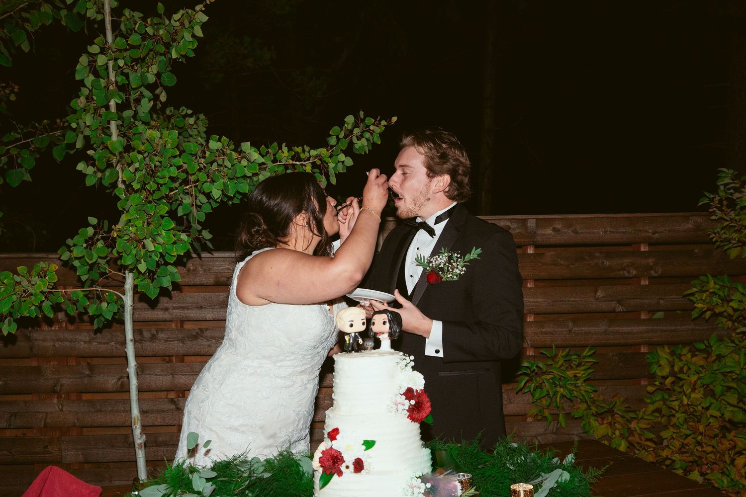 A couple shares their first dance at a rustic outdoor wedding venue with wooden walls.
