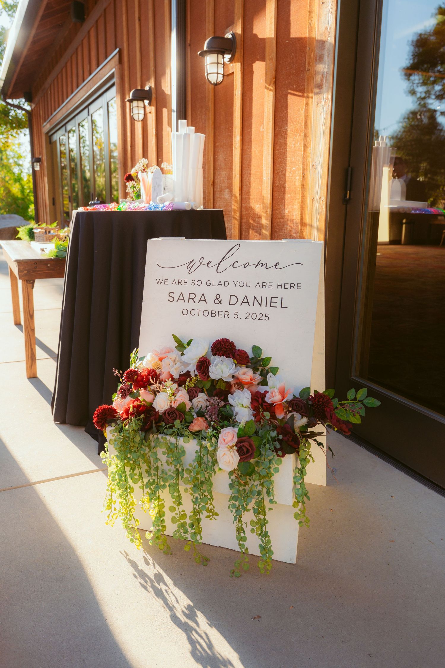 Wedding welcome sign with floral decorations and couple's names displayed at venue entrance.