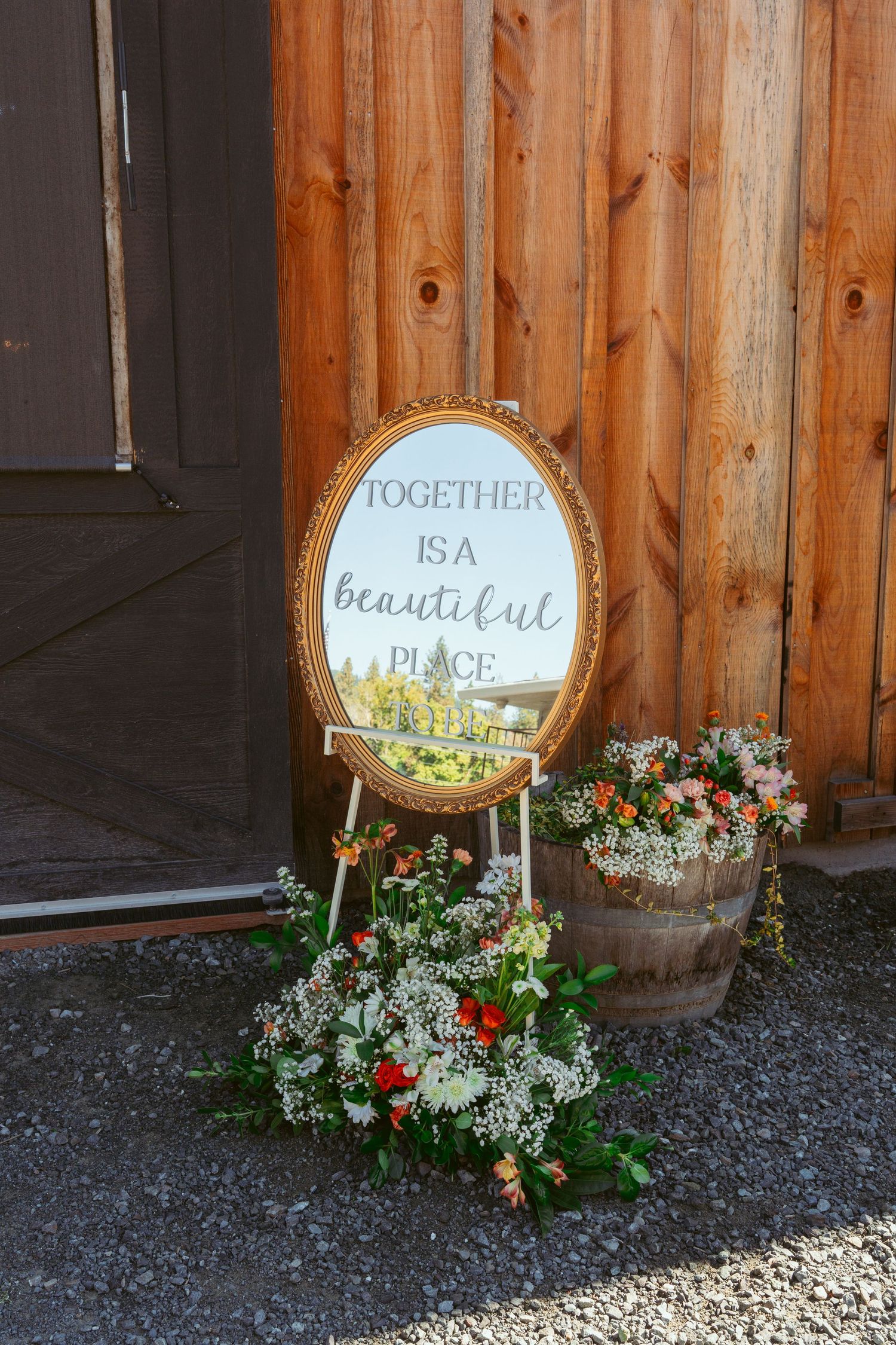 Decorative mirror signs with floral arrangements reading 'Together is Beautiful' against wooden wall.