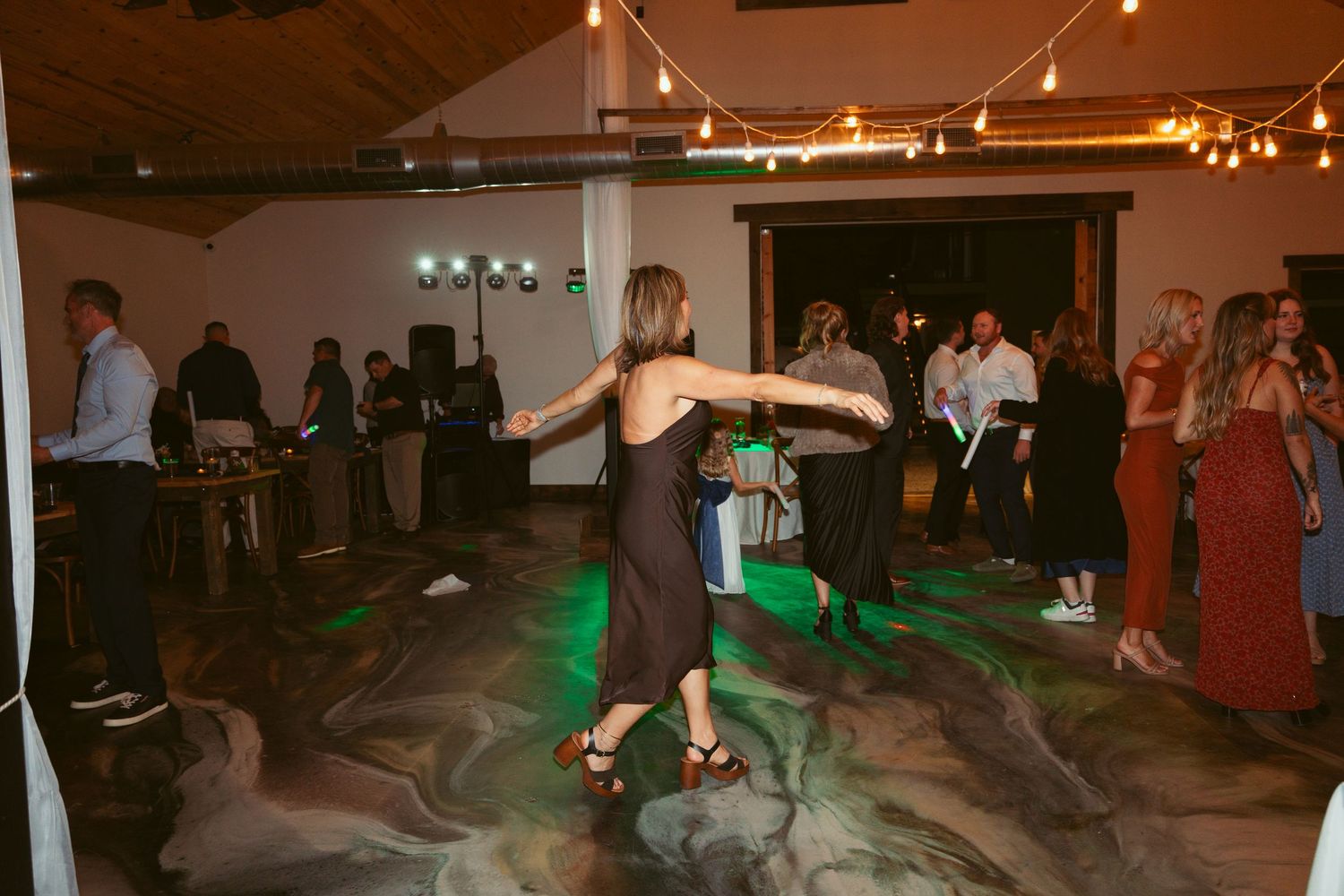 Wedding reception venue with string lights and guests dancing in a festive atmosphere.