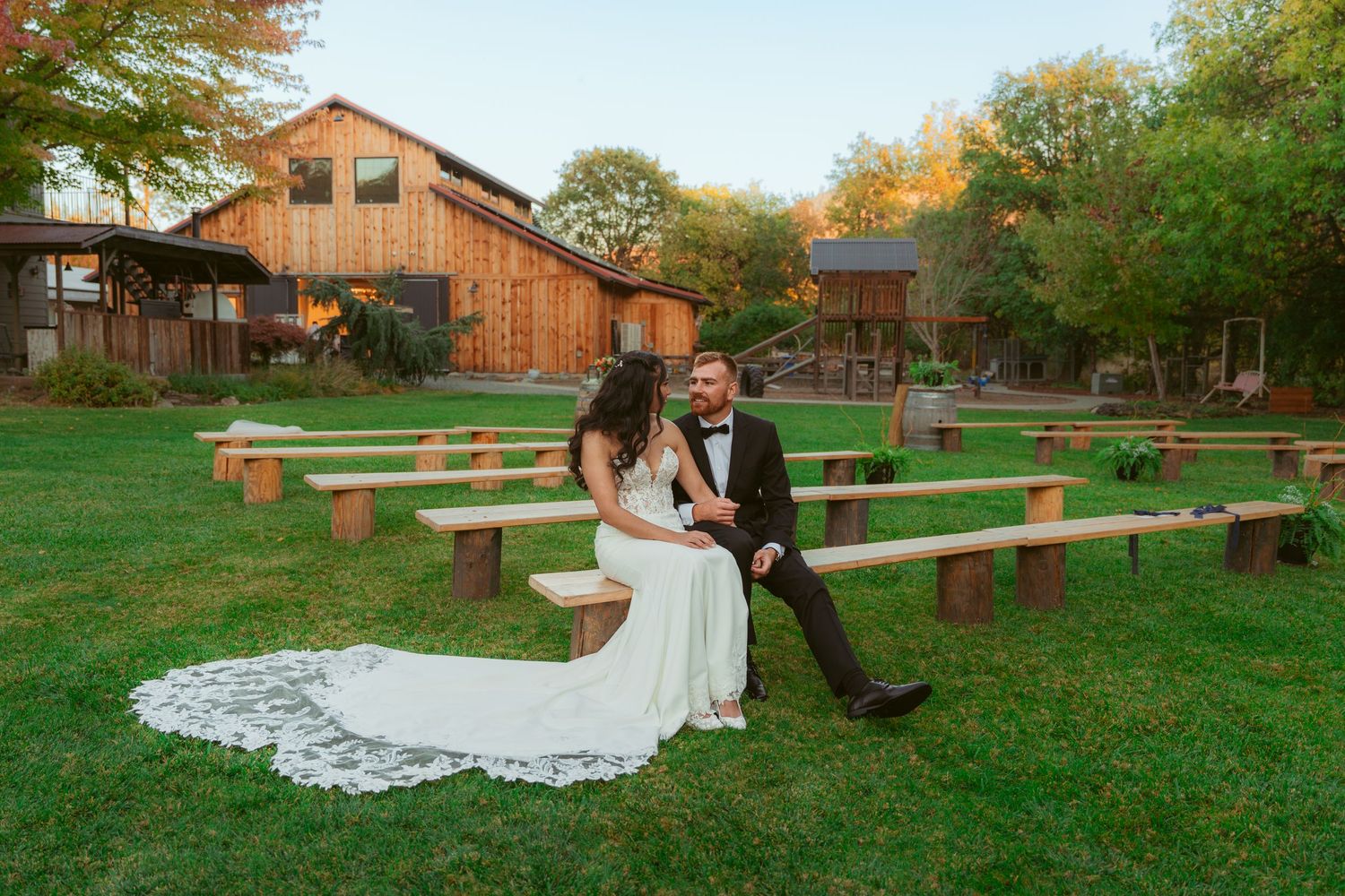 Wedding couple shares intimate moment on rustic farm property with wooden fences.