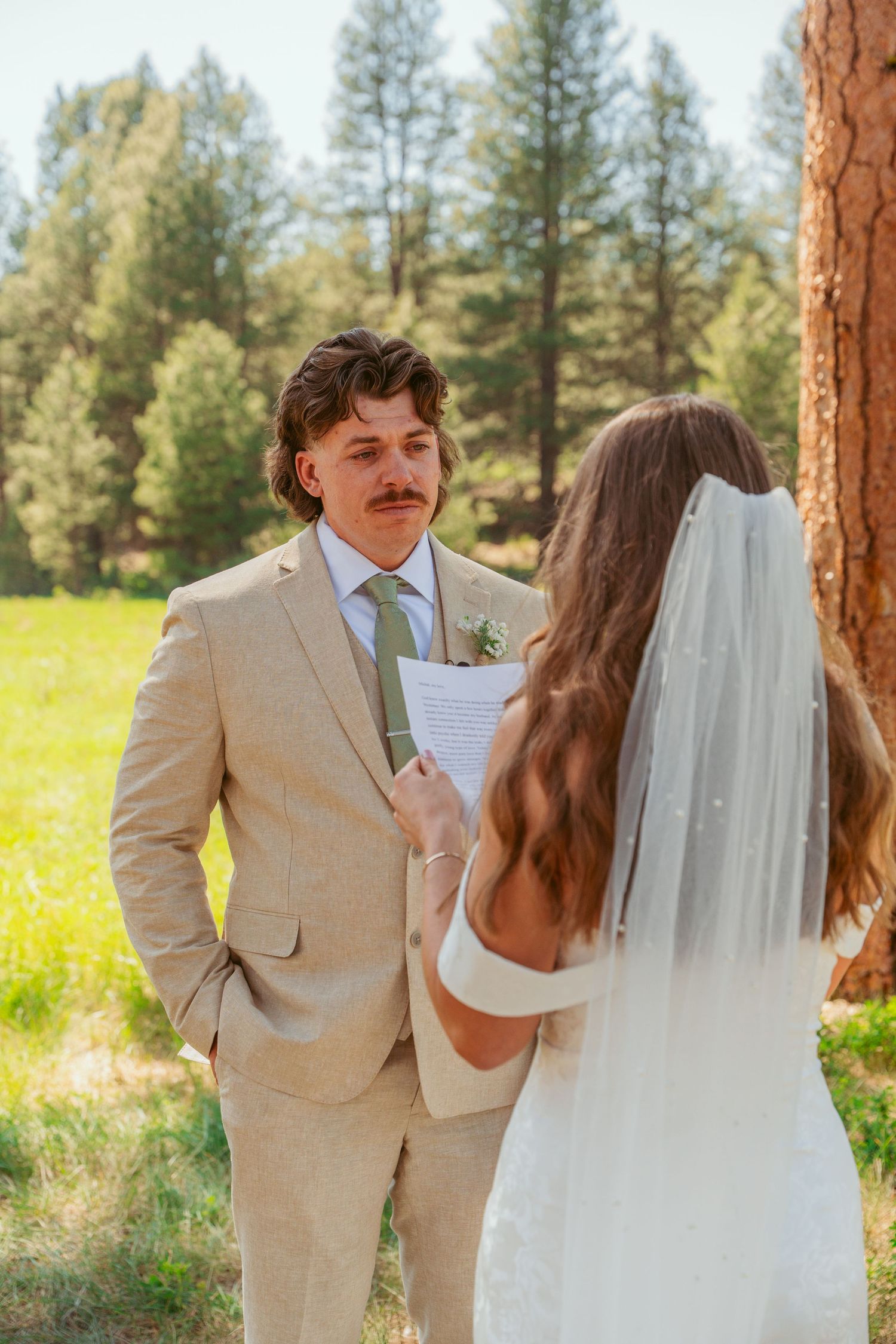 A couple shares intimate vows among tall pine trees on their wedding day.