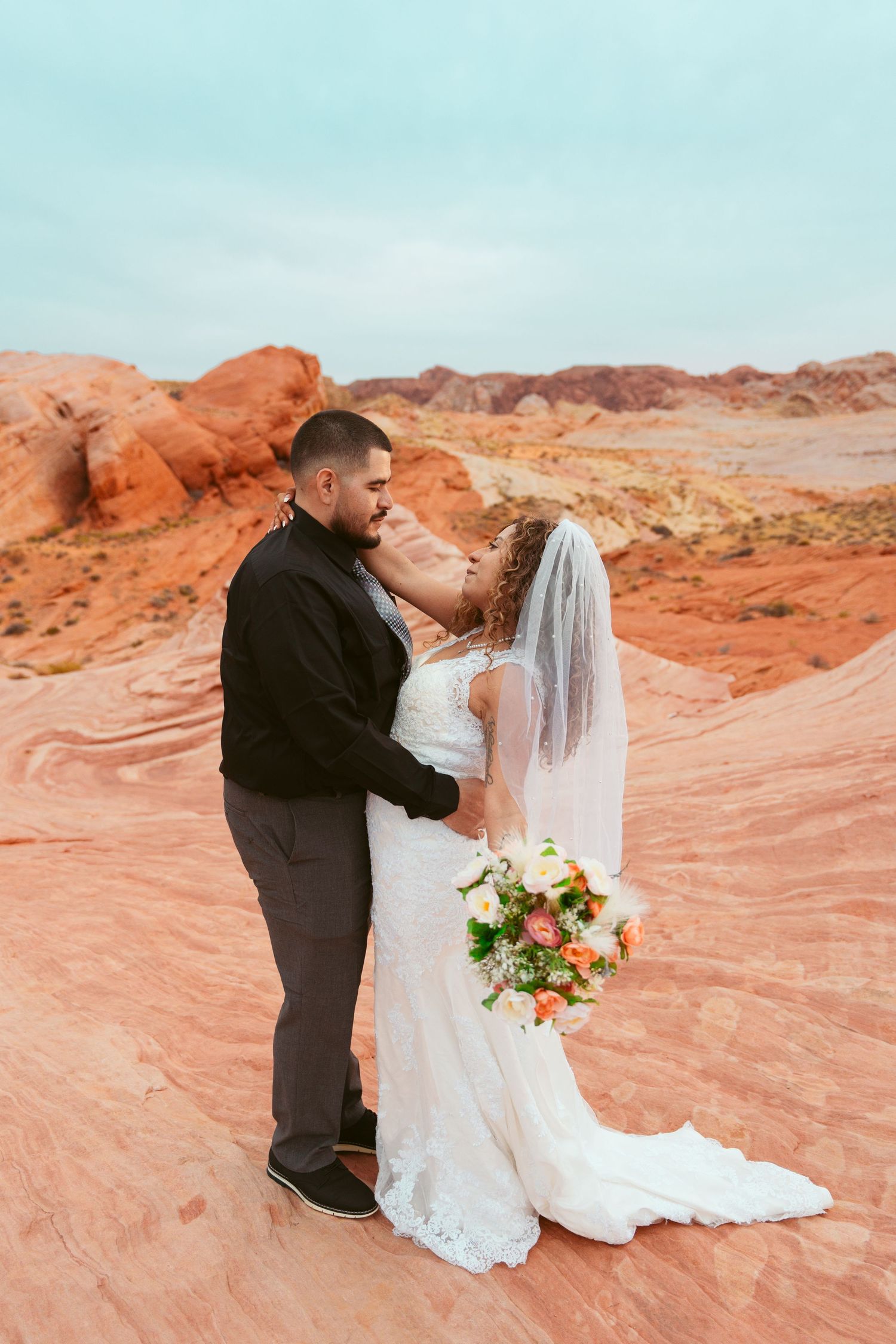 Bride and groom share intimate moments while standing on vibrant orange sandstone formations.