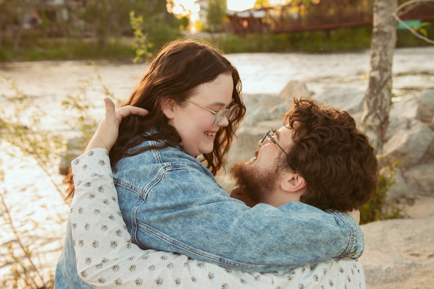 Couple embracing in warm sunlight by the water.