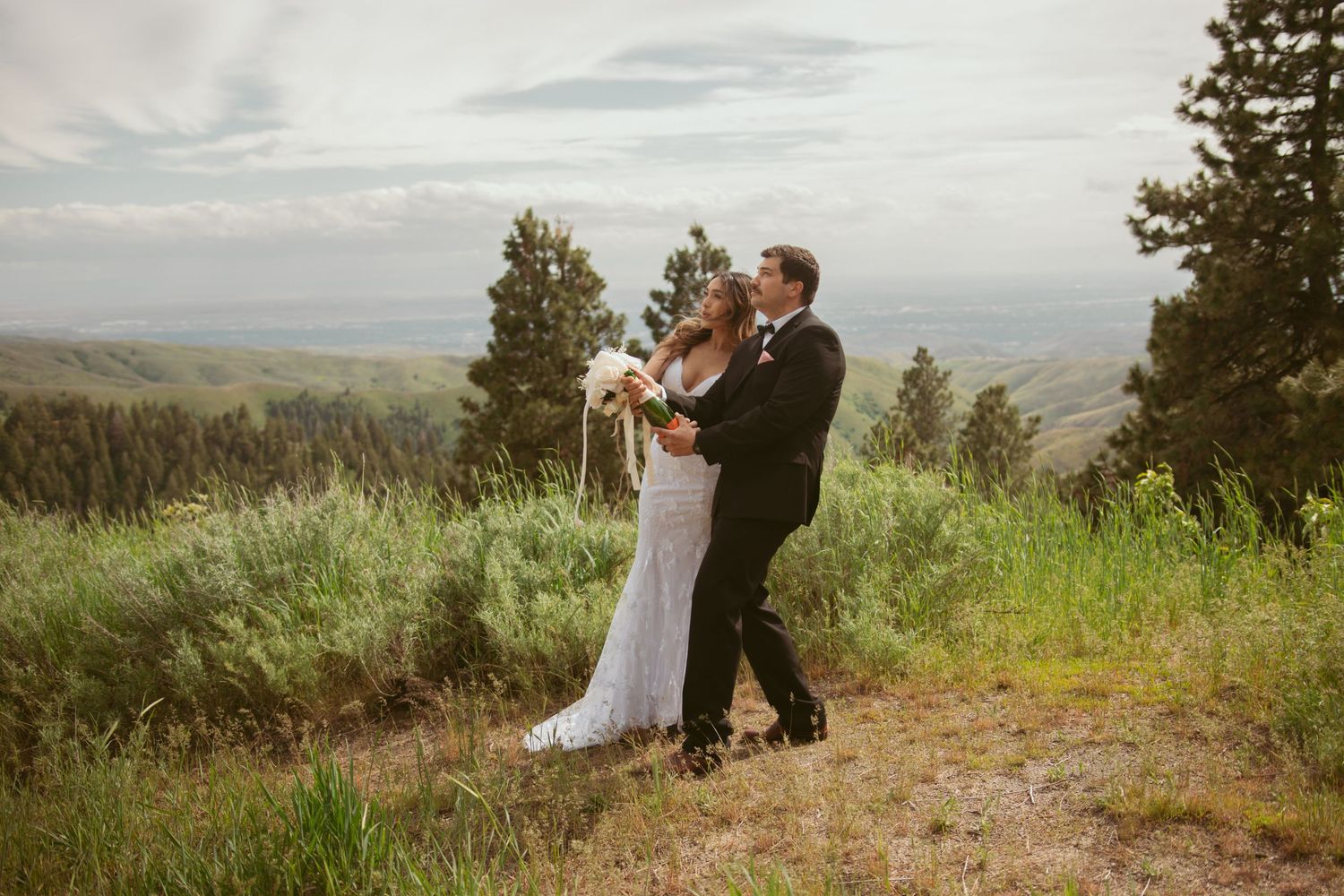 Wedding couple embracing on a scenic mountain overlook during their outdoor ceremony.