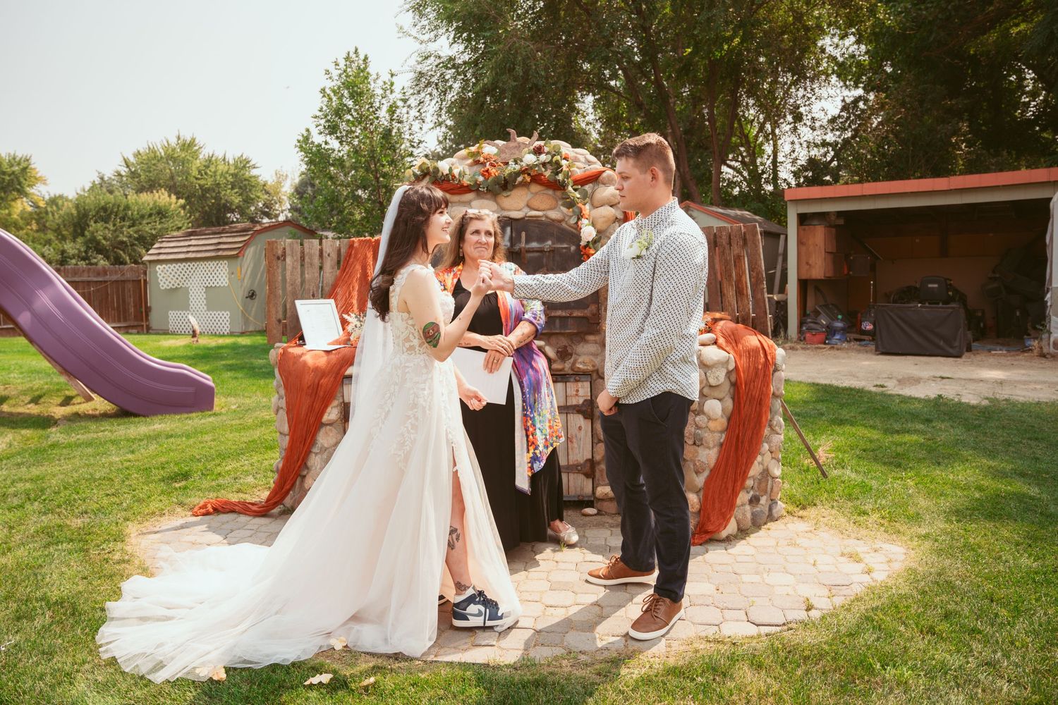 Wedding celebration in outdoor garden setting with rustic brick walls and natural greenery.