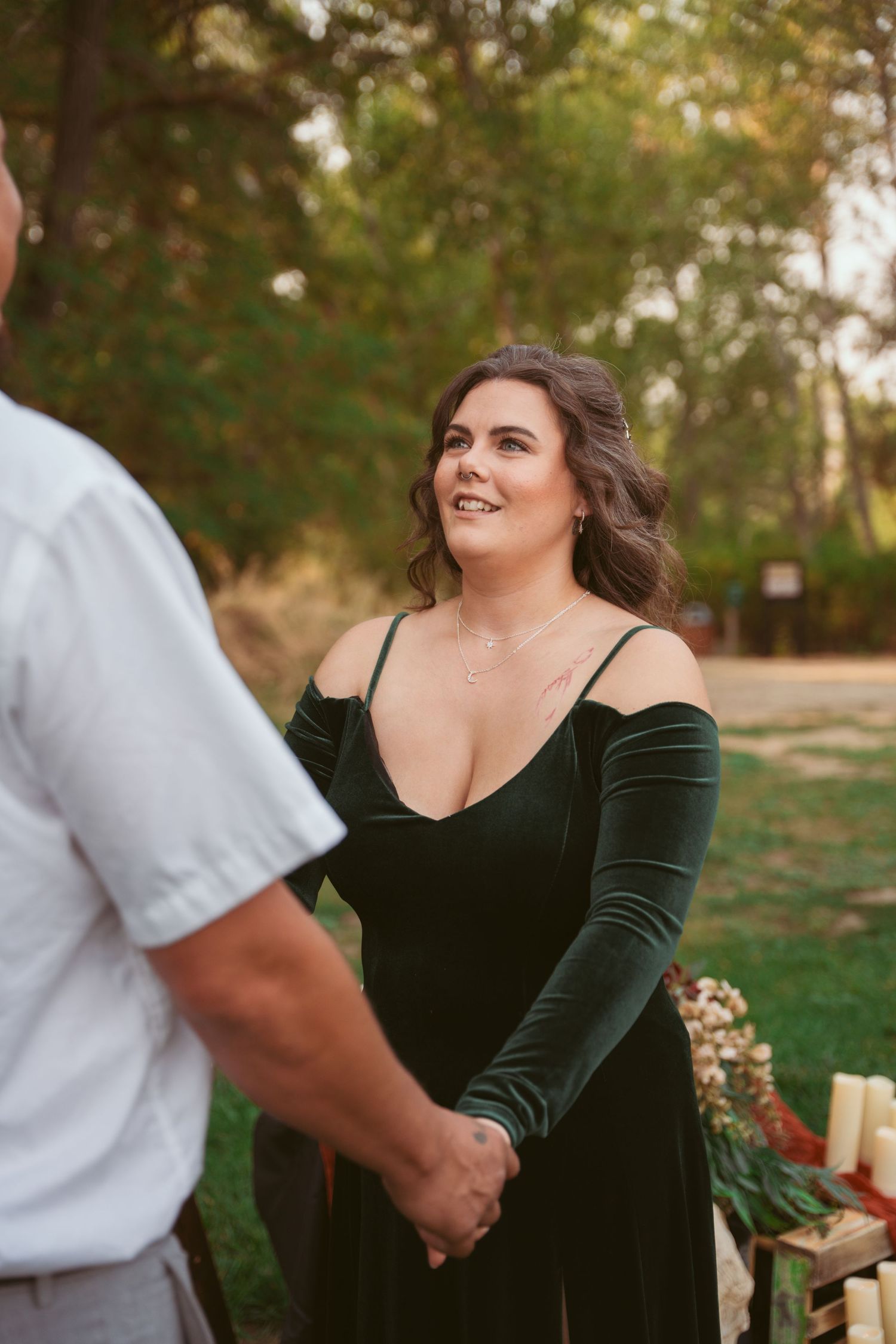 Person wearing black velvet dress smiles during outdoor event.