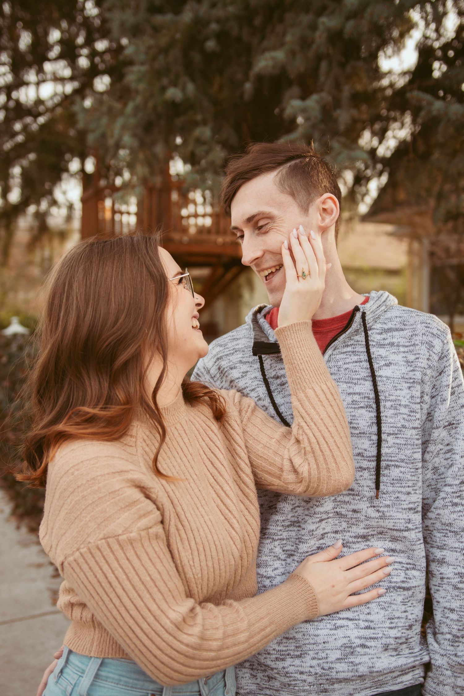 A candid moment of joy between a couple wearing casual sweaters outdoors.